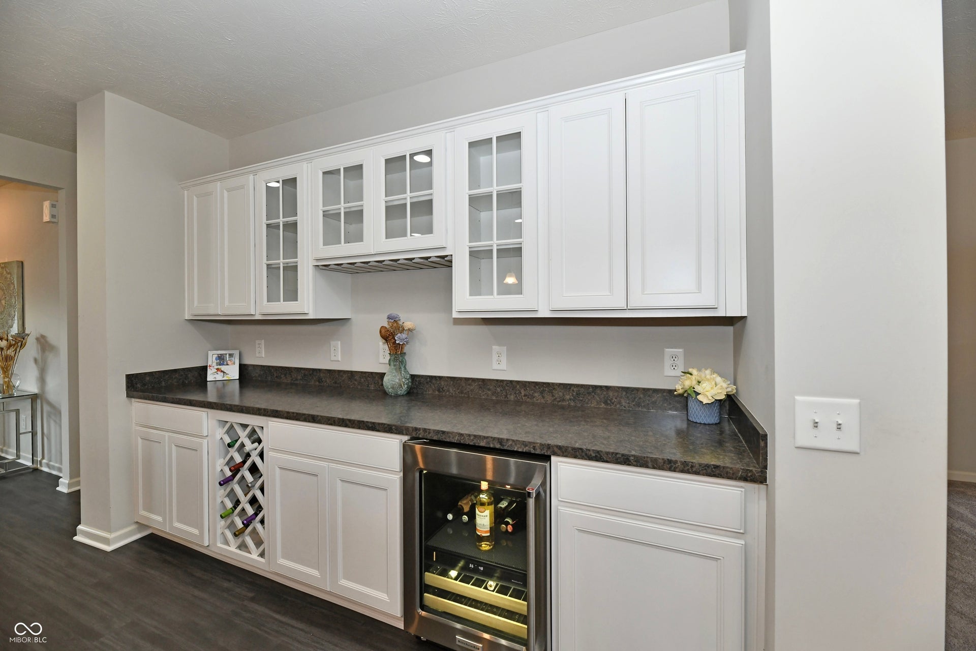 White cabinetry with glass-front upper cabinets, built-in wine rack, and a beverage refrigerator
