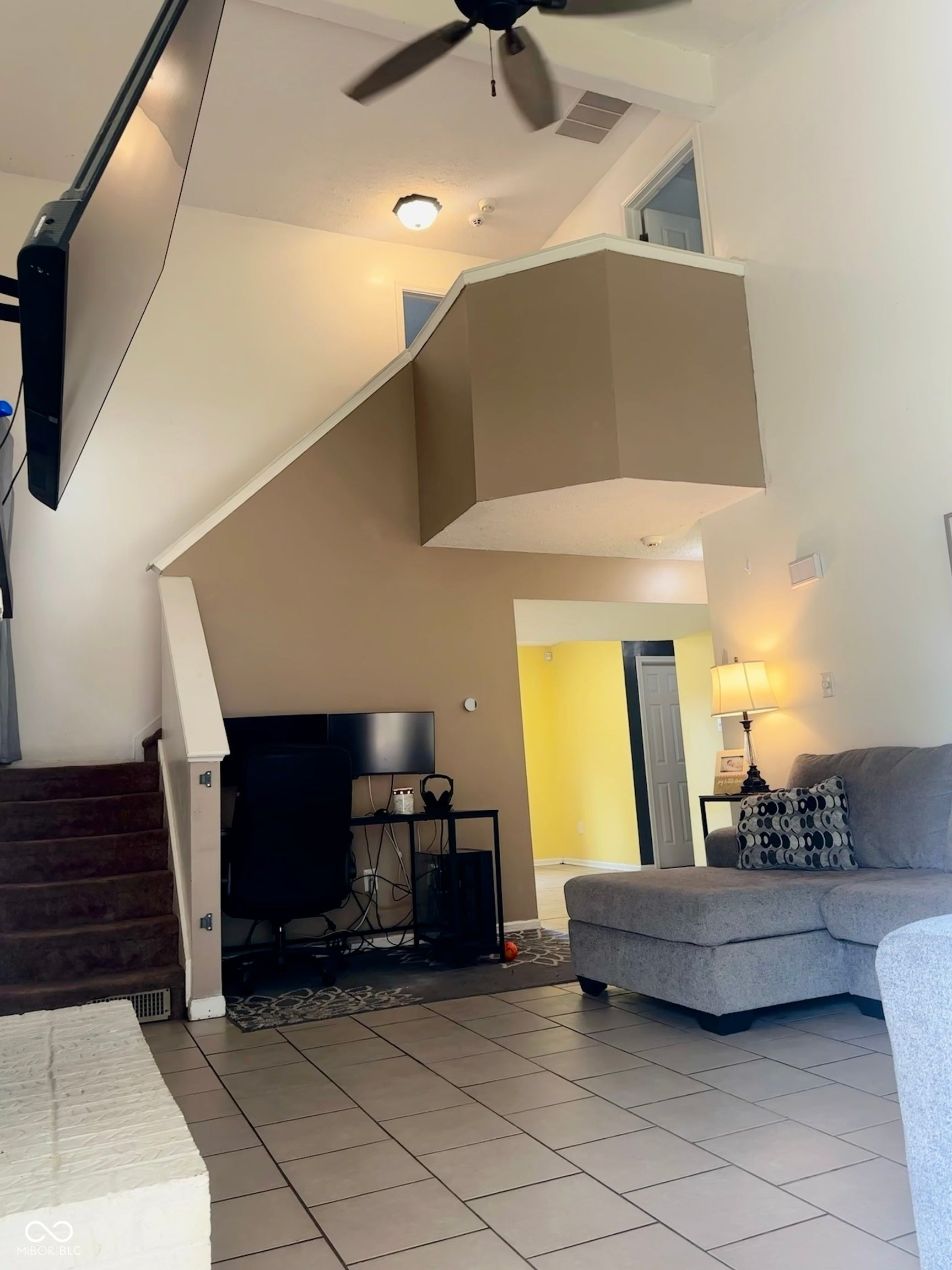 Tile flooring, staircase with carpeted treads, ceiling fan with integrated lighting, overhead lighting fixture, upper-level landing