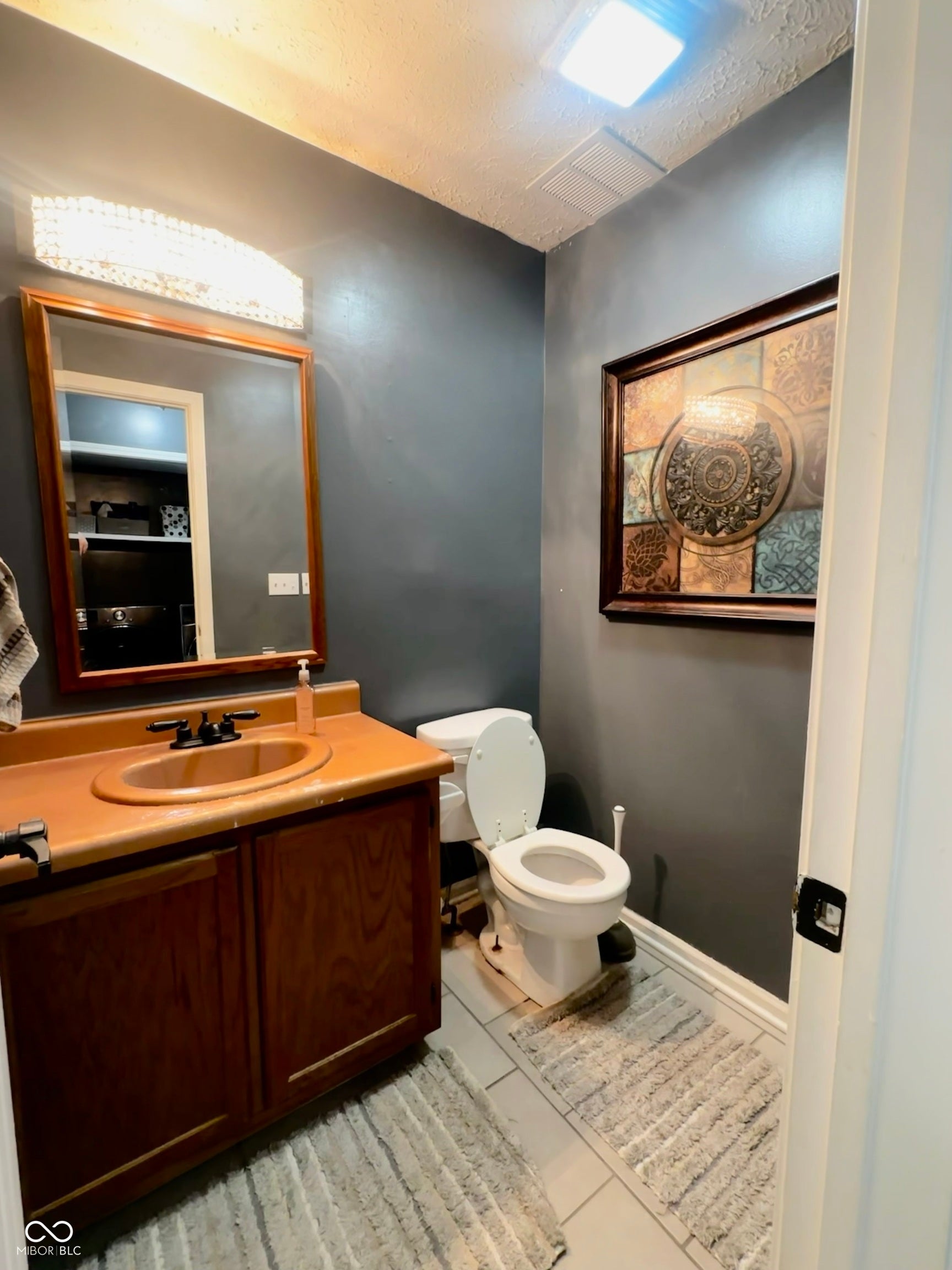Wood-finish vanity with an integrated sink, rectangular mirror, and overhead decorative light fixture