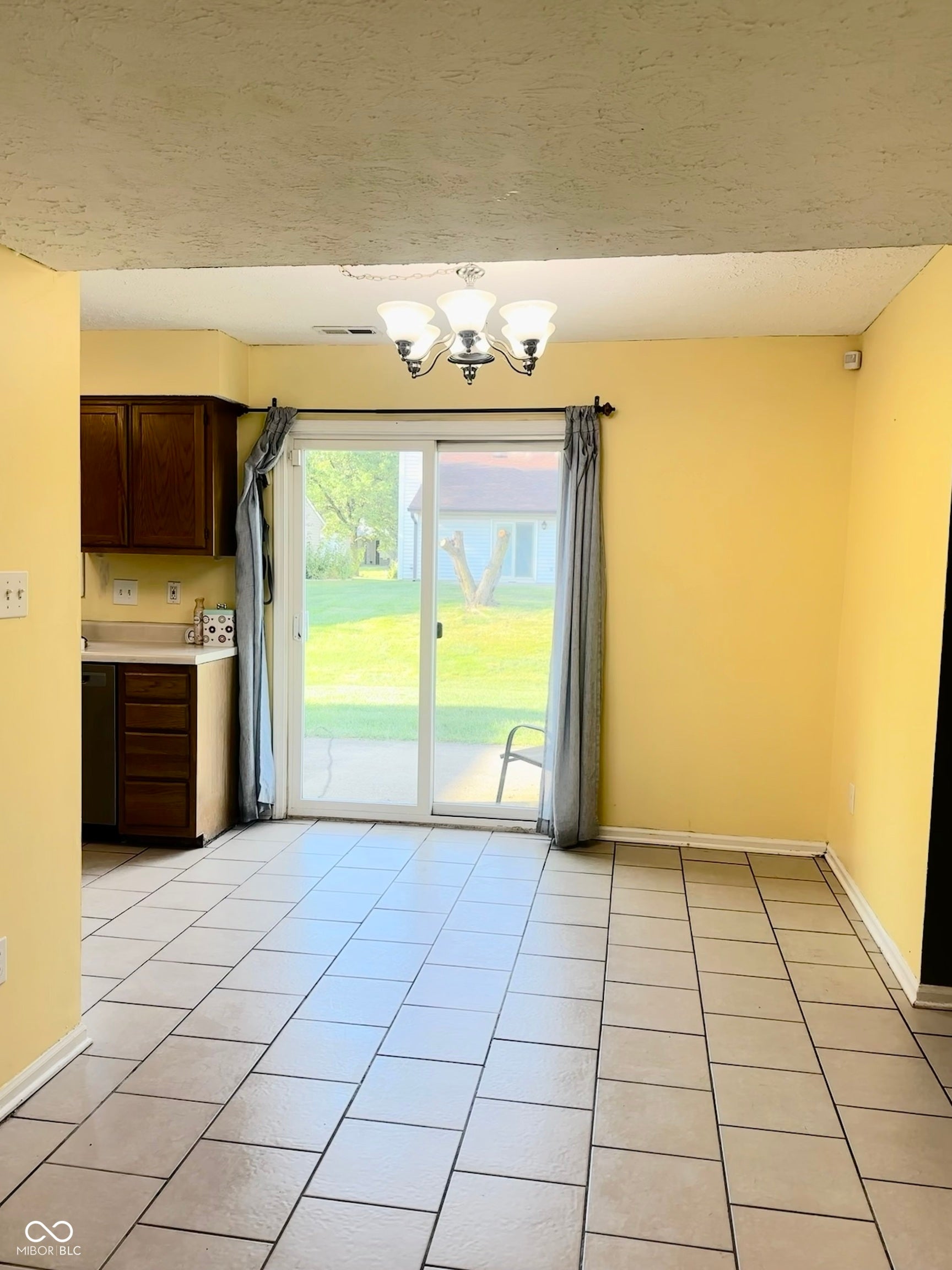 Spacious dining area featuring tile flooring, a multi-bulb ceiling fixture, and direct patio access through sliding glass doors