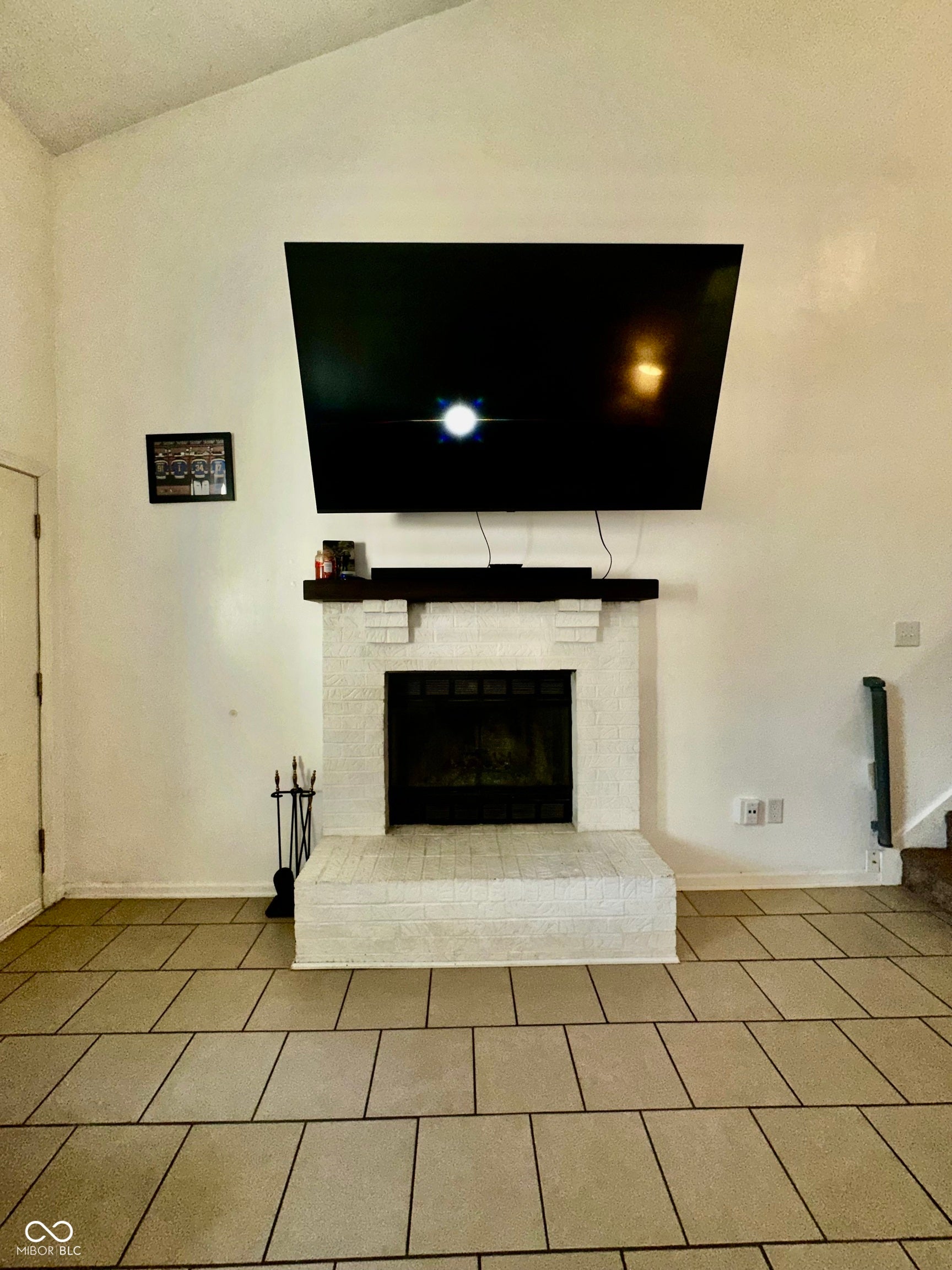 Vaulted ceiling complementing a brick-surround fireplace with a dark wood-finish mantel and a tile hearth