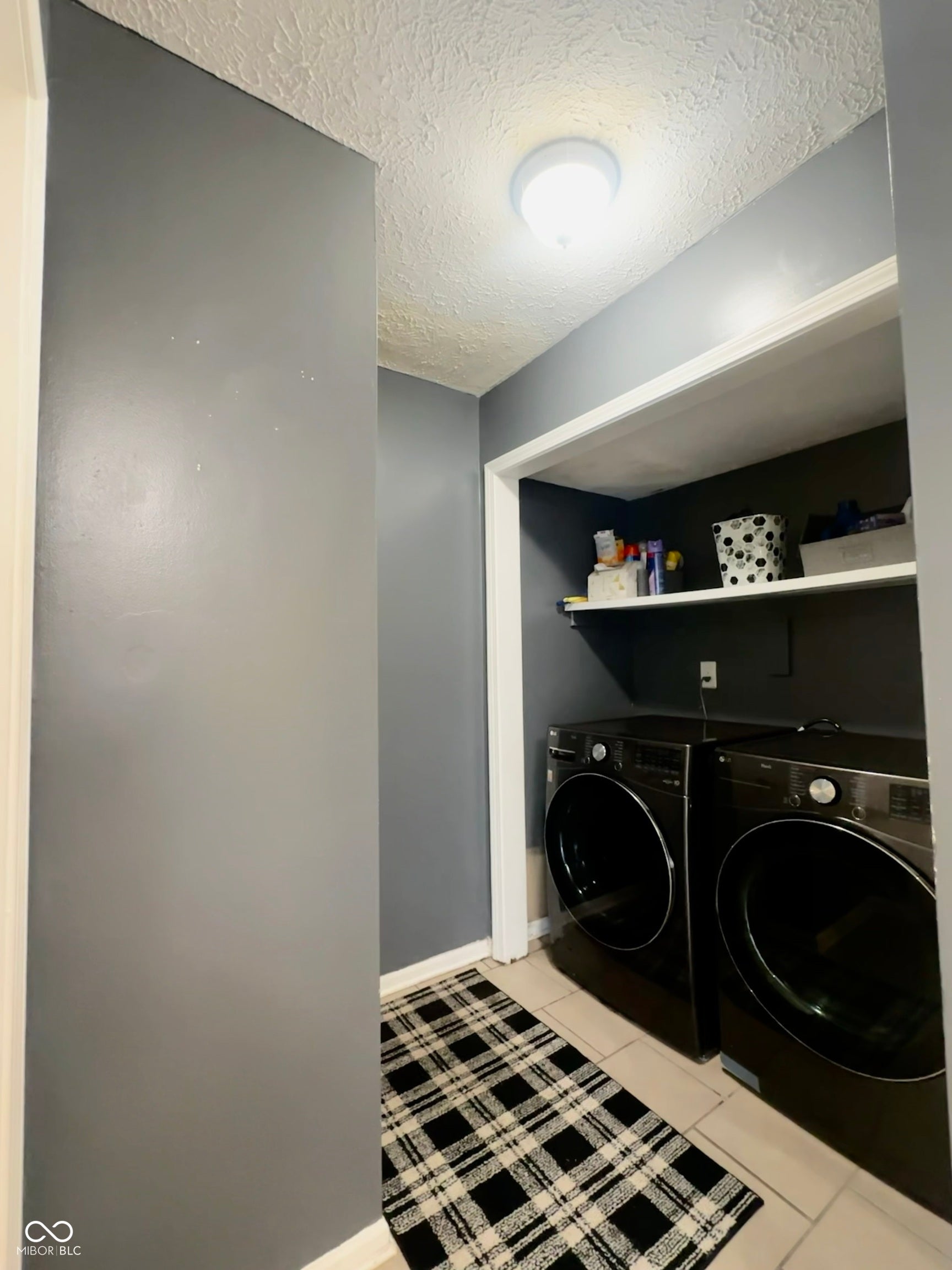 Laundry area featuring tile flooring, built-in shelving, and a ceiling-mounted light fixture
