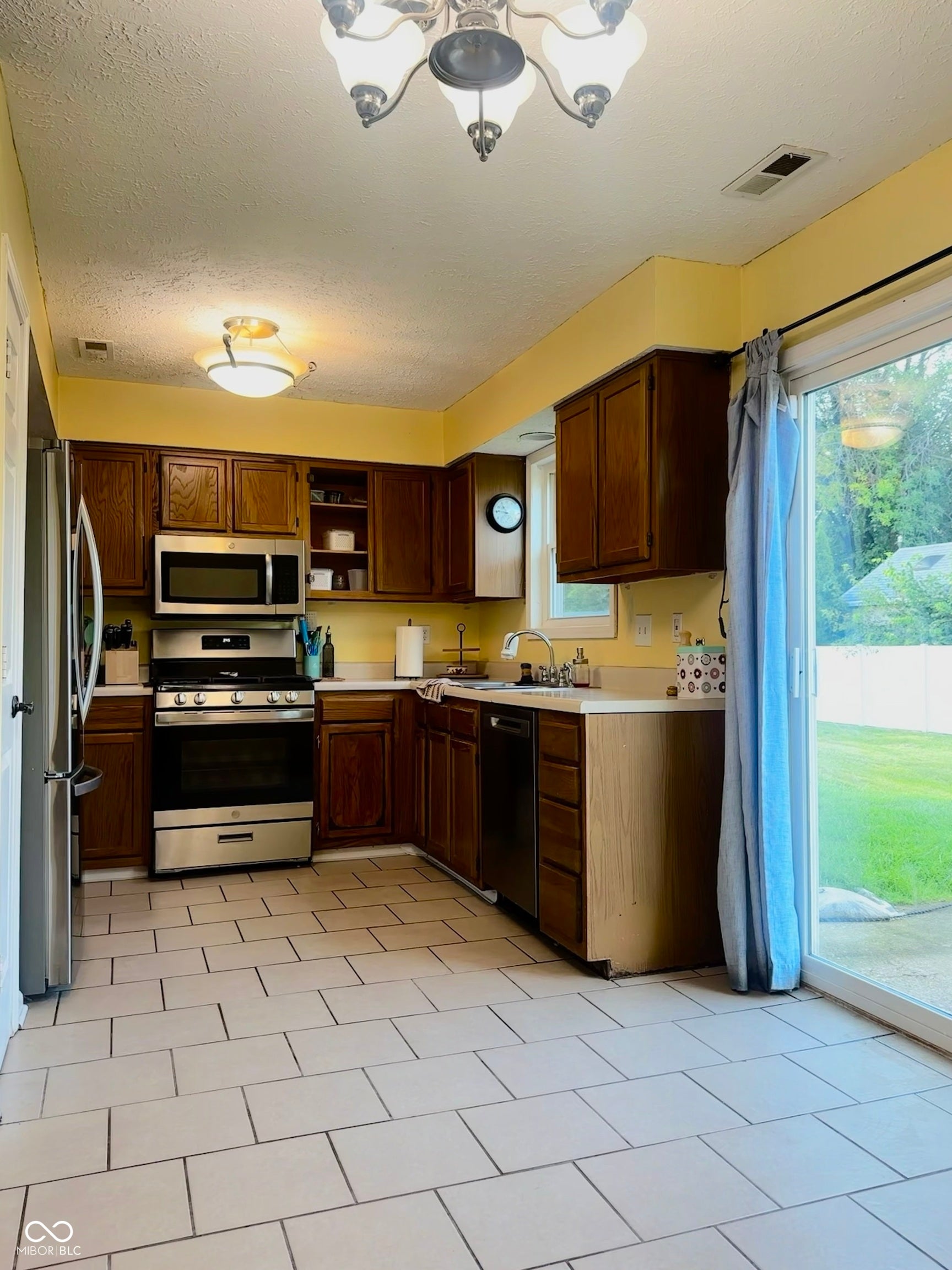 Kitchen featuring ample cabinetry, stainless steel appliances, tile flooring, and a sliding glass door