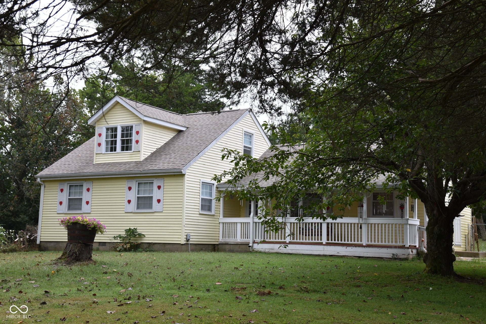 Light yellow siding exterior with a covered front porch featuring white railing