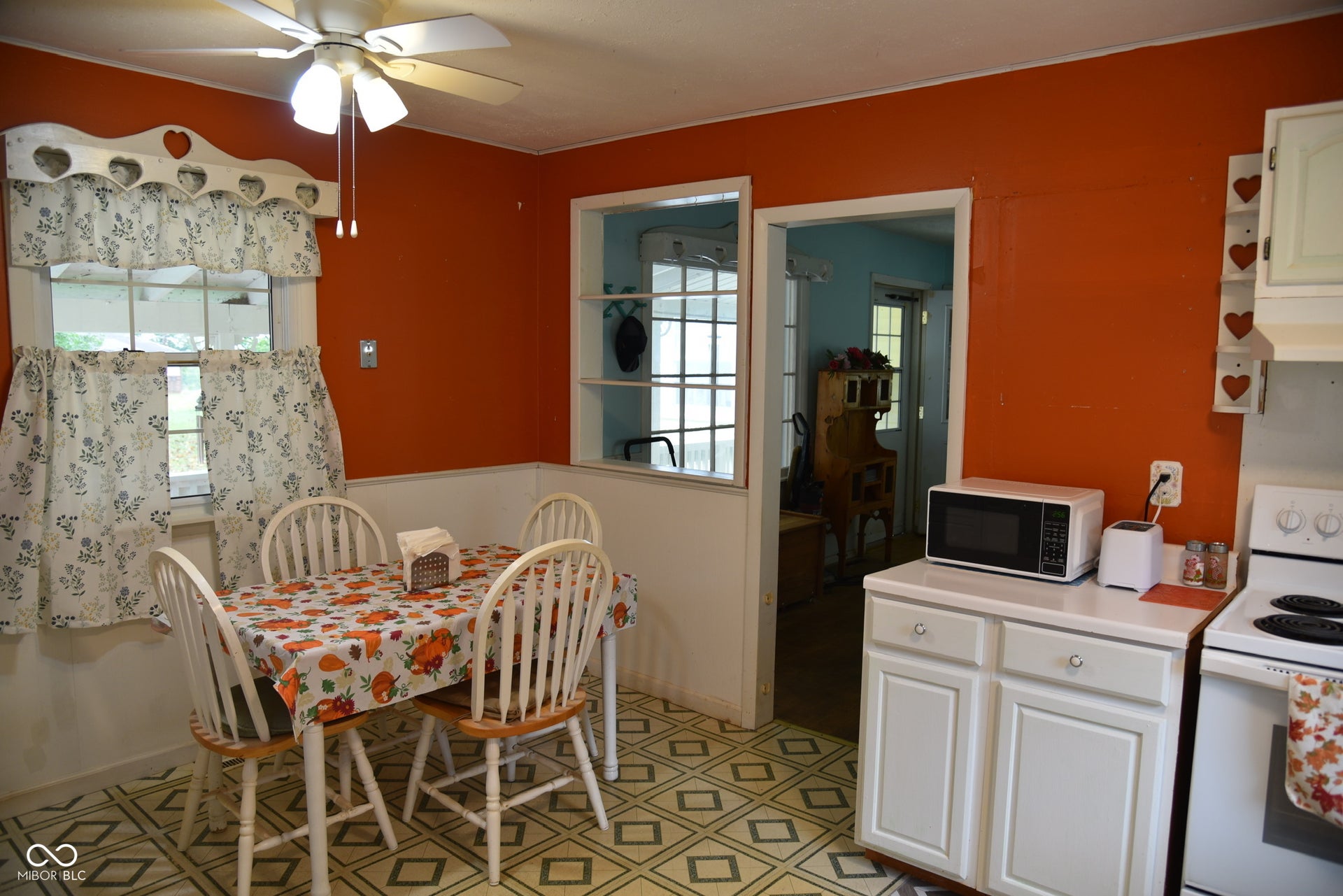 Galley kitchen with patterned flooring, white cabinetry, and a ceiling fan with light fixture