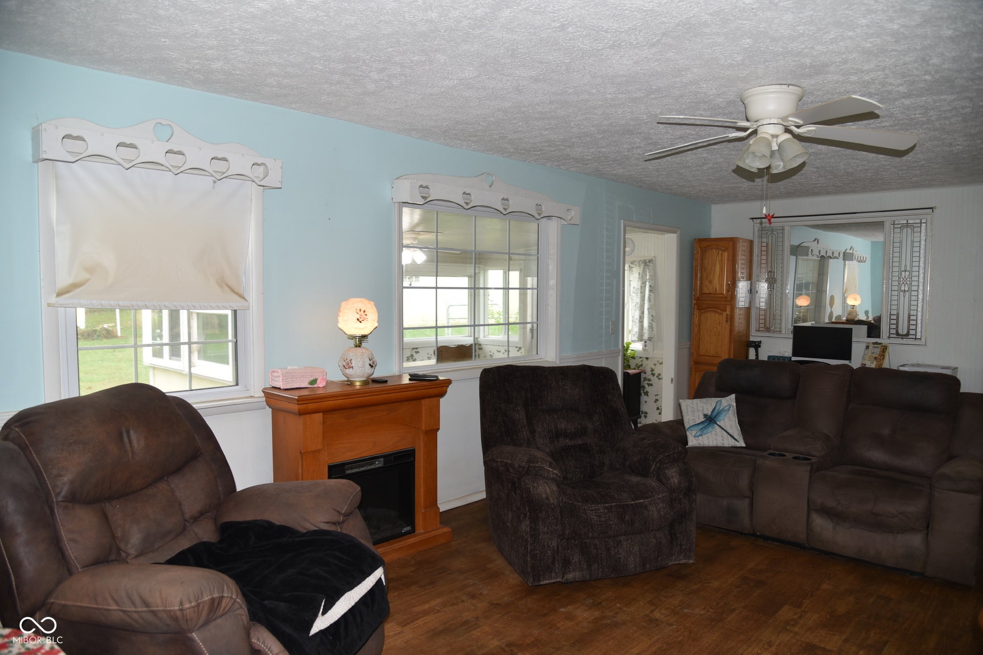 Wood-finish flooring, light blue wall paint, and a ceiling fan with integrated lighting