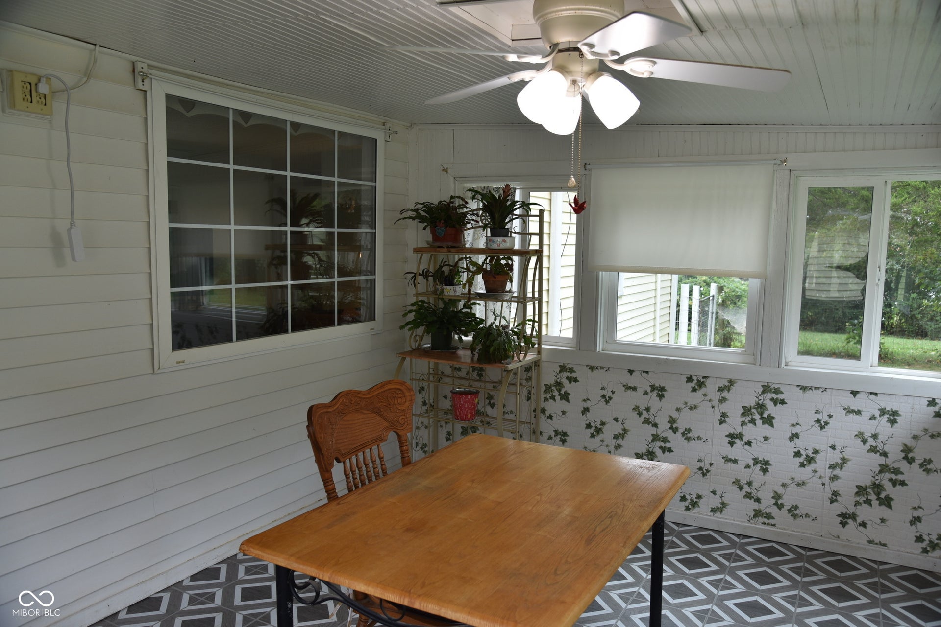 Enclosed porch featuring a ceiling fan with integrated lighting, multiple windows with white trim, and patterned floor tiles
