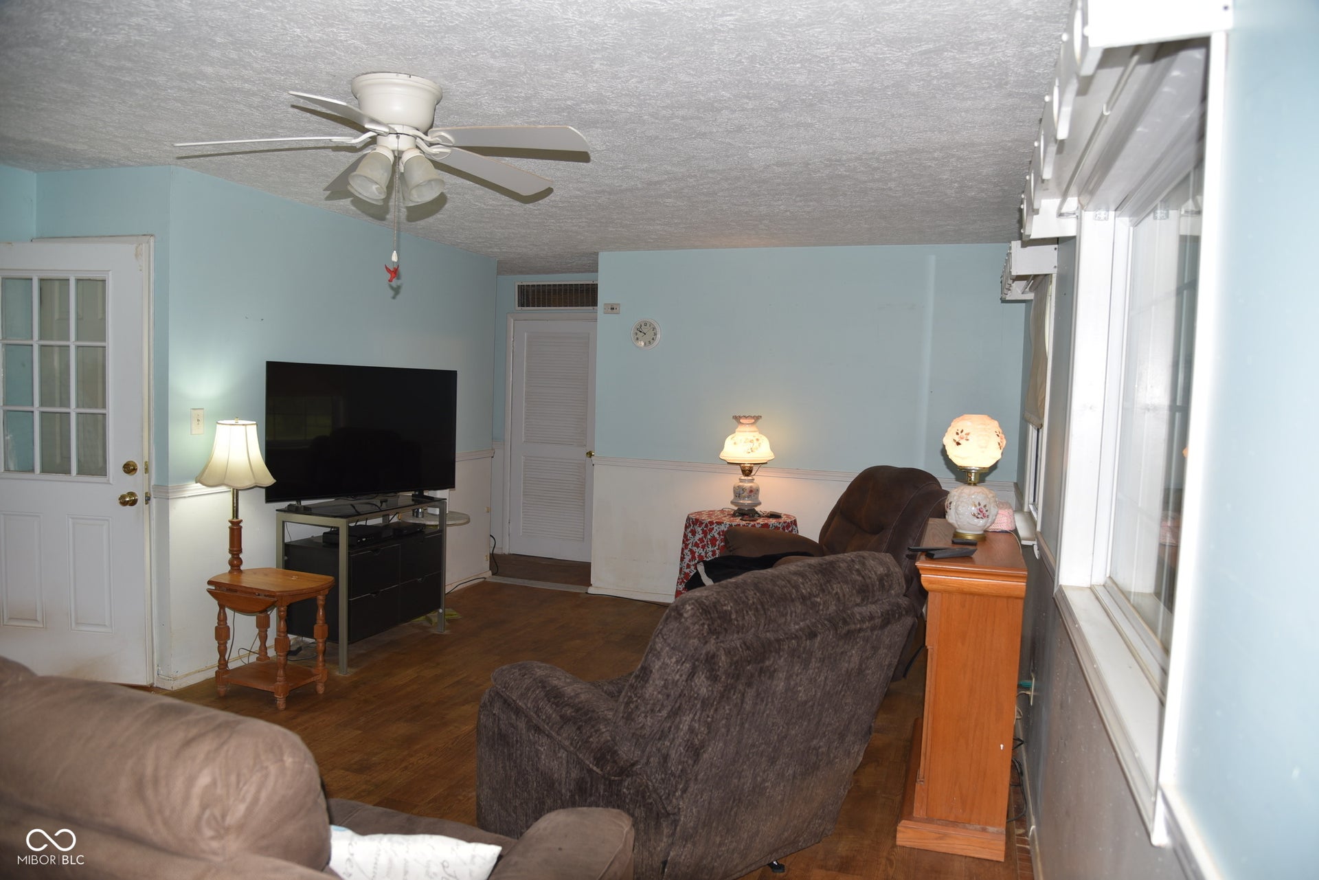 Wood-finish flooring throughout, complemented by a white ceiling fan with integrated lighting
