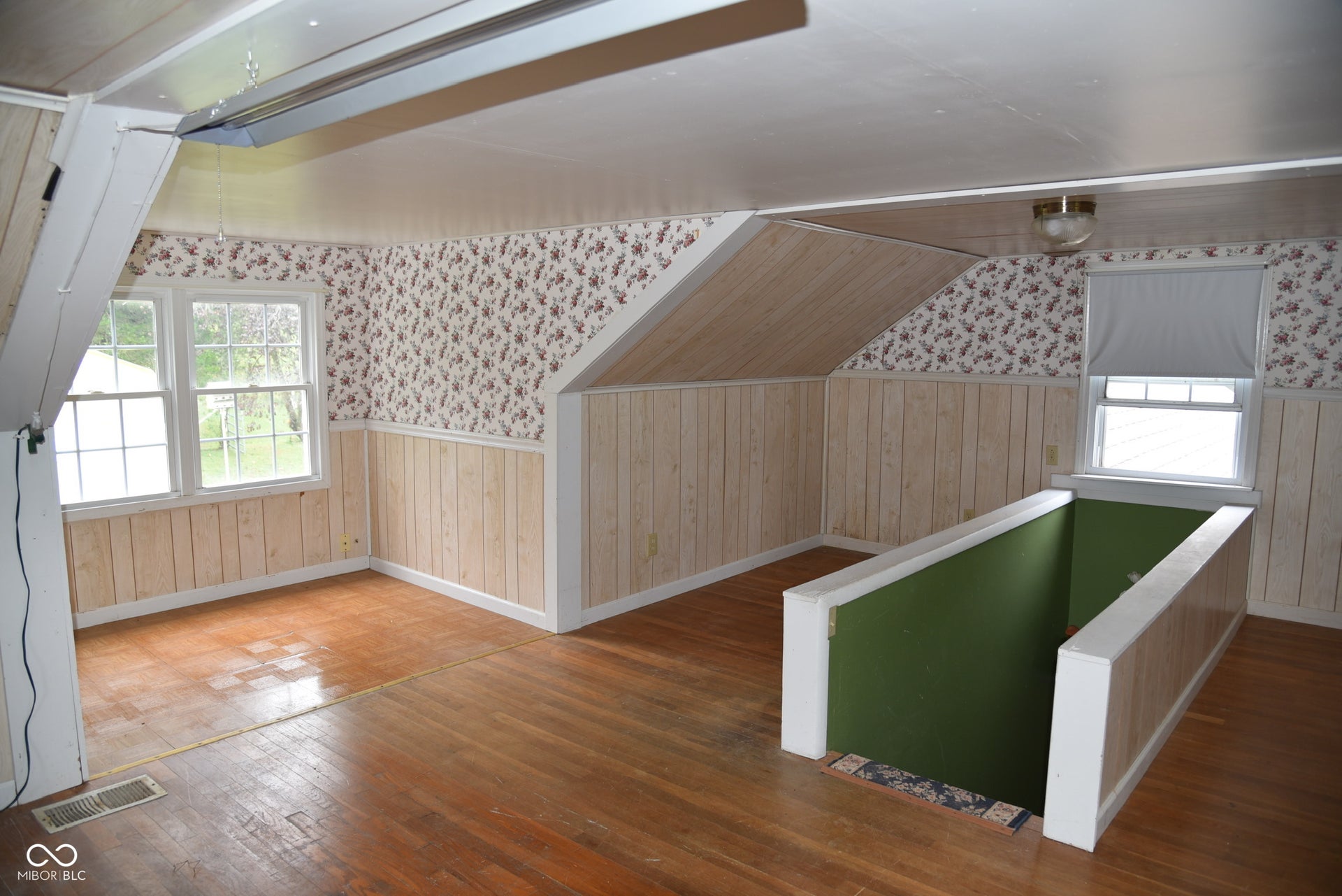 Hardwood flooring, twin windows, wainscoting, floral wallpaper accents, and a built-in overhead light fixture