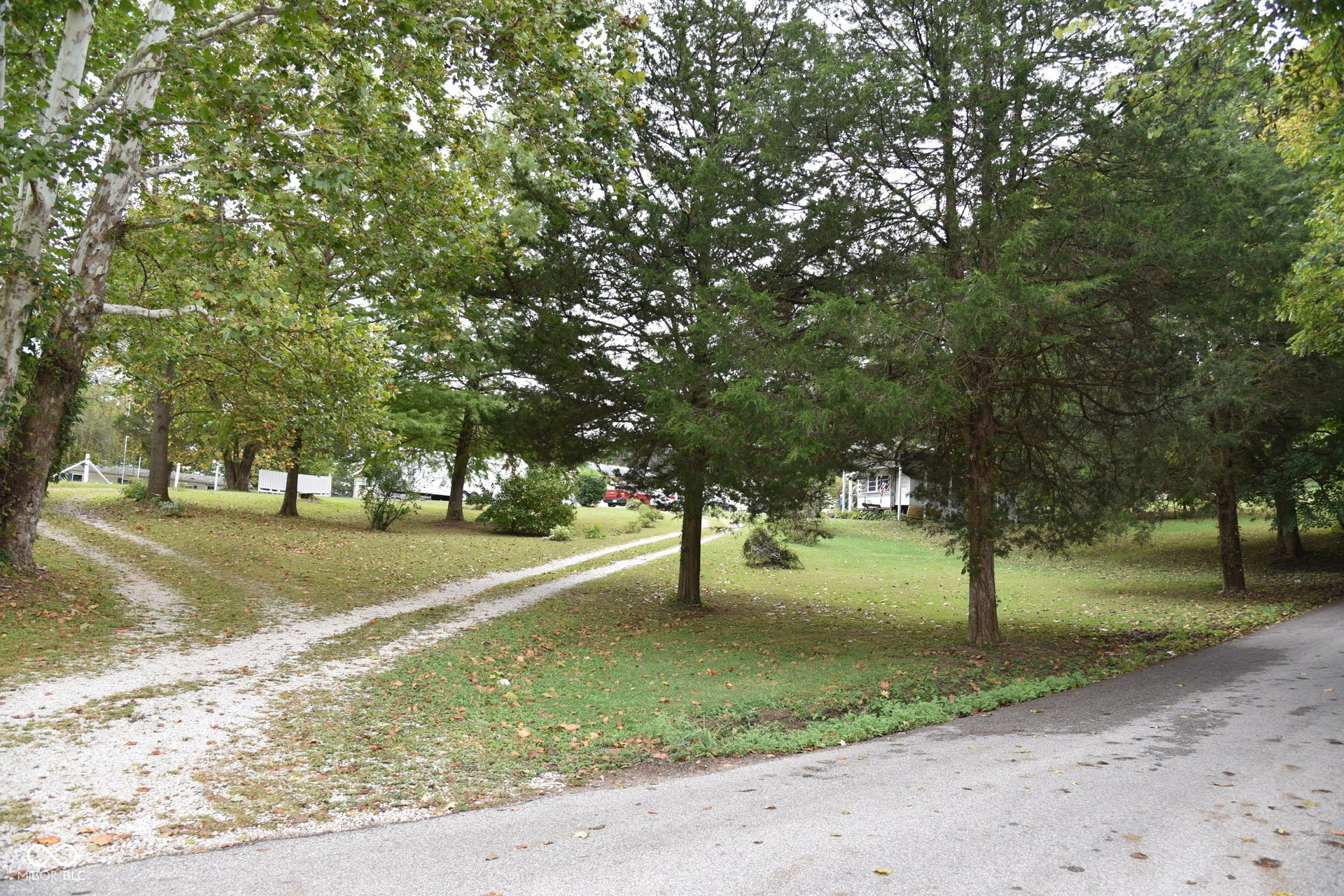 Gravel driveways, mature trees, and a grassy expanse