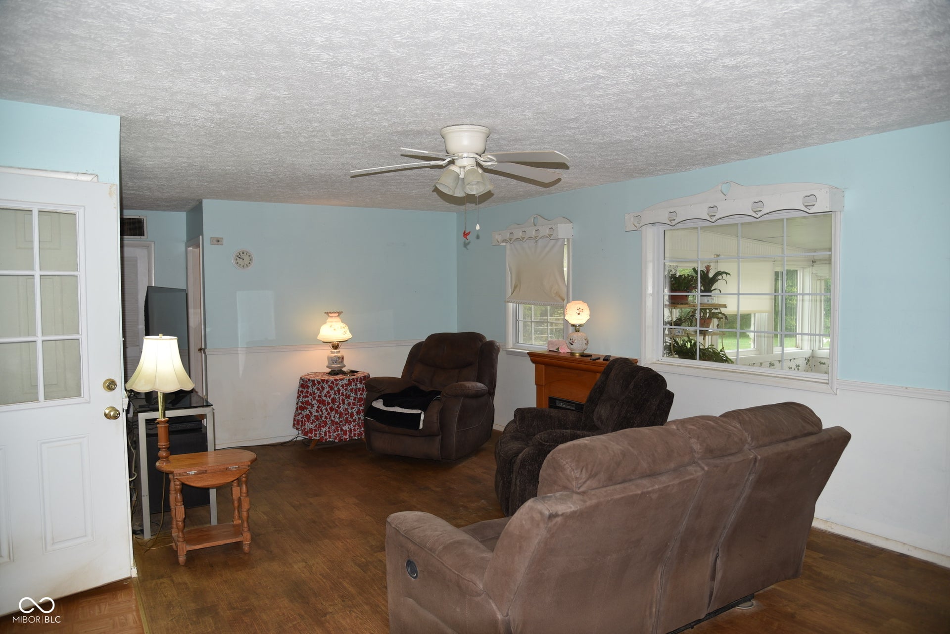 Wood-finish flooring, two large windows, ceiling fan, and a paneled door with glass inserts