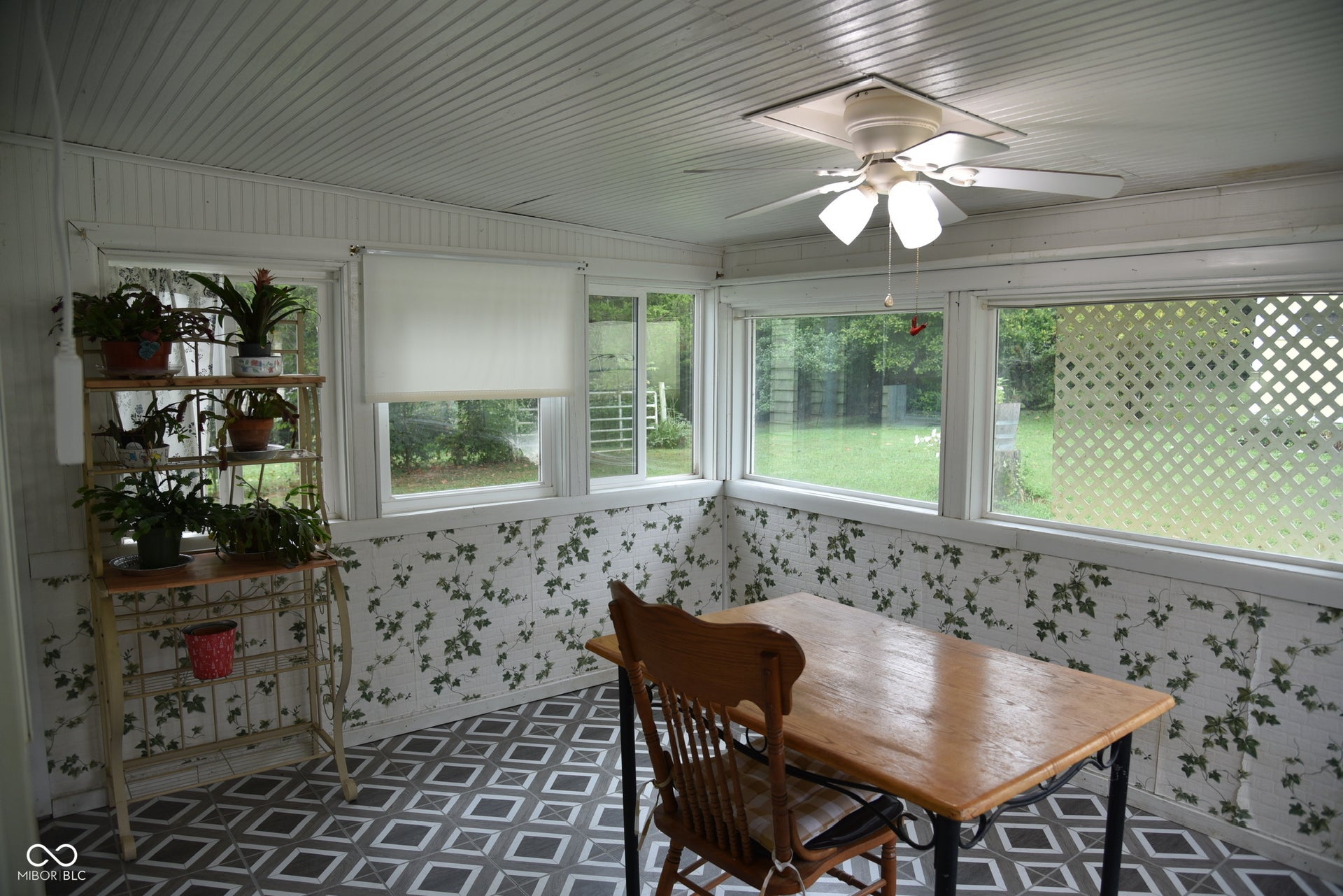 Enclosed porch with a slatted ceiling, patterned flooring, multiple windows, and a ceiling fan with integrated lighting