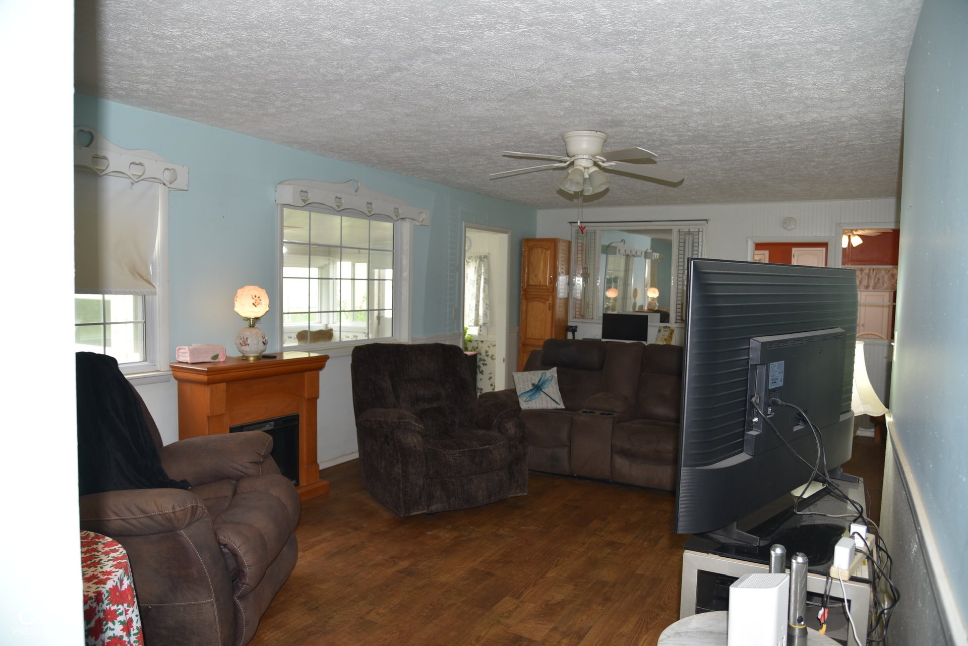 Wood-finish flooring, two large windows, and a ceiling fan with integrated lighting