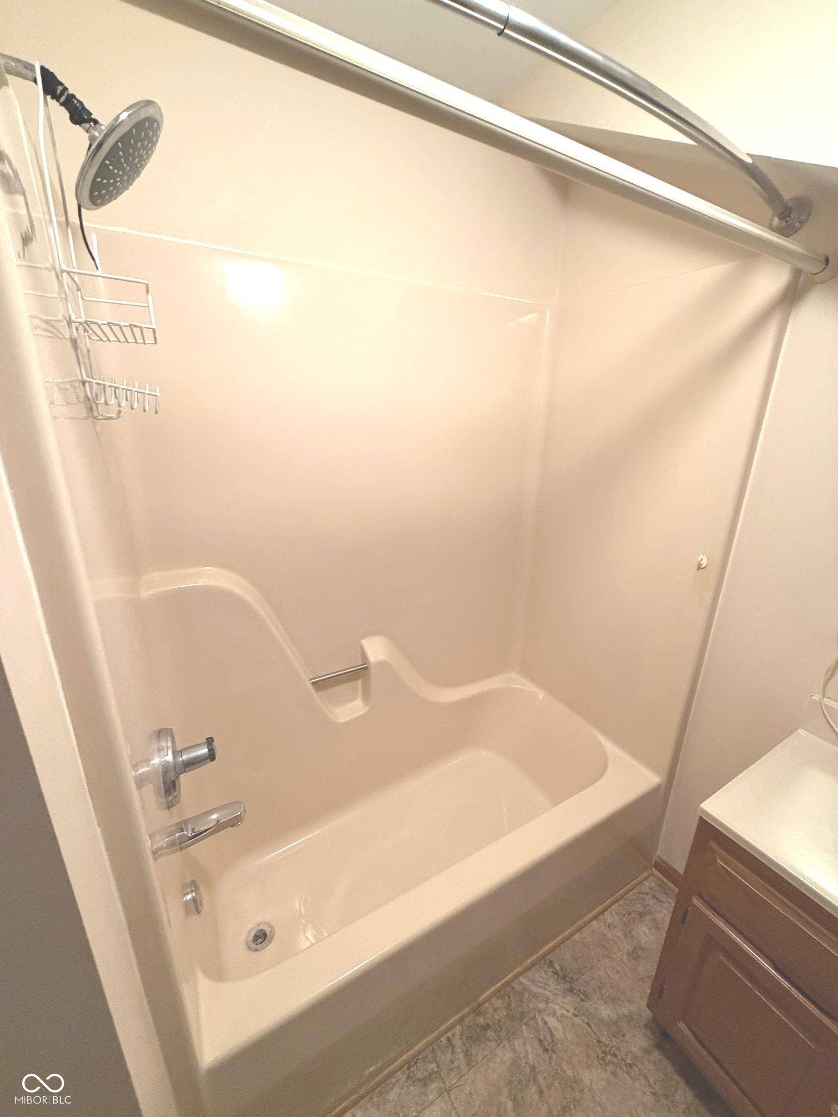 Built-in bathtub with integrated shower, chrome fixtures, and a curved shower rod