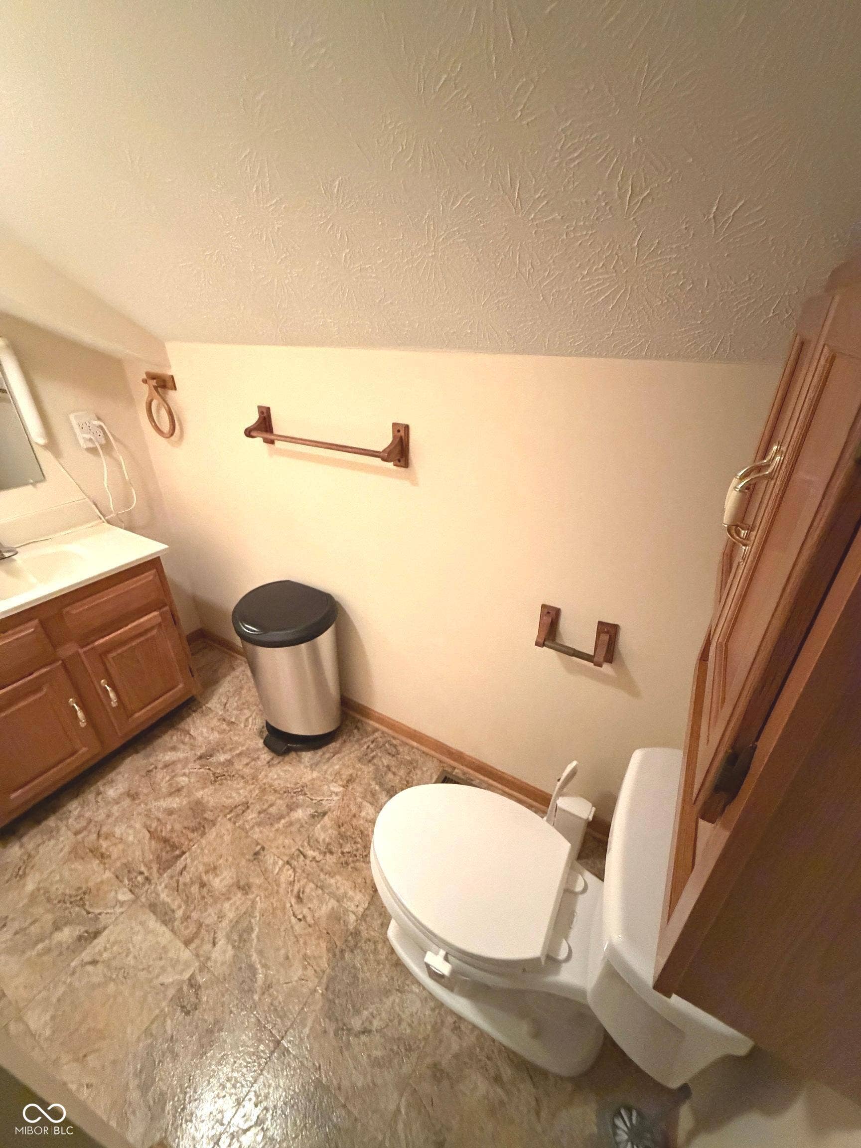 Vanity with wood-finish cabinetry, white countertop, and integrated sink