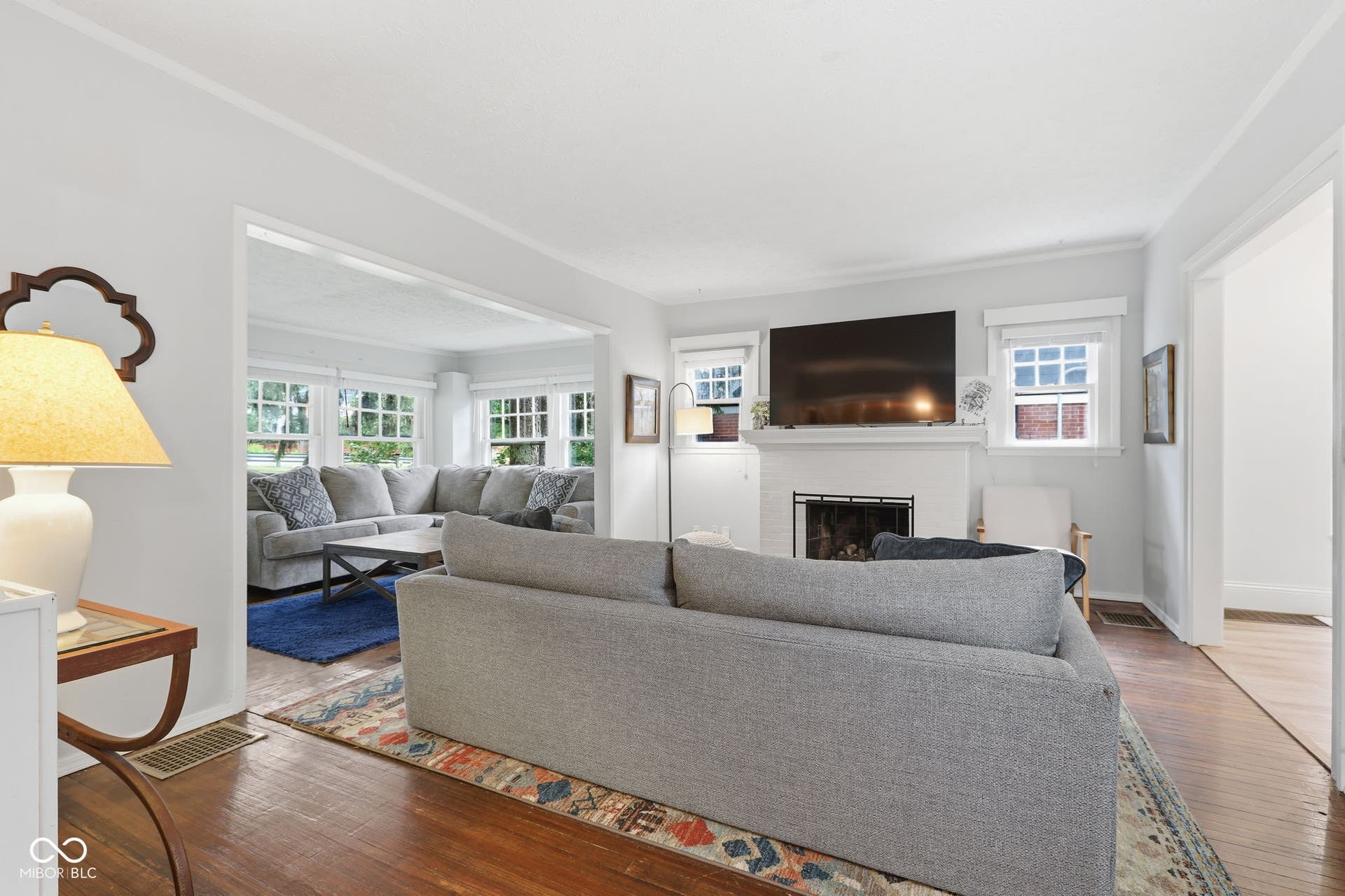 Hardwood flooring, white painted brick fireplace, built-in mantel, recessed fireplace insert, and crown molding