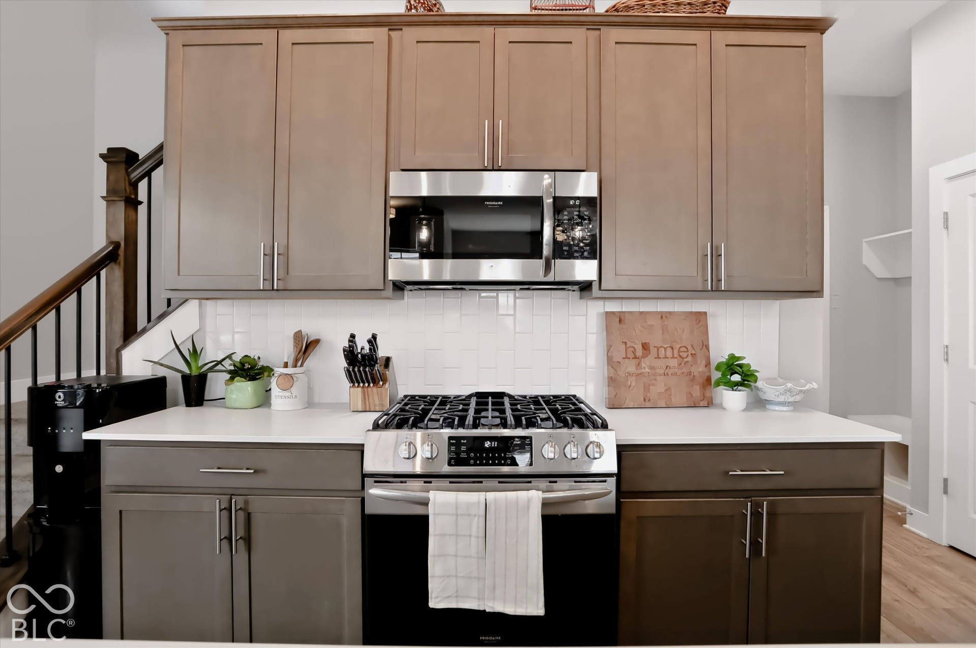 Stainless steel microwave, white subway tile backsplash, stainless steel gas range, and white countertops