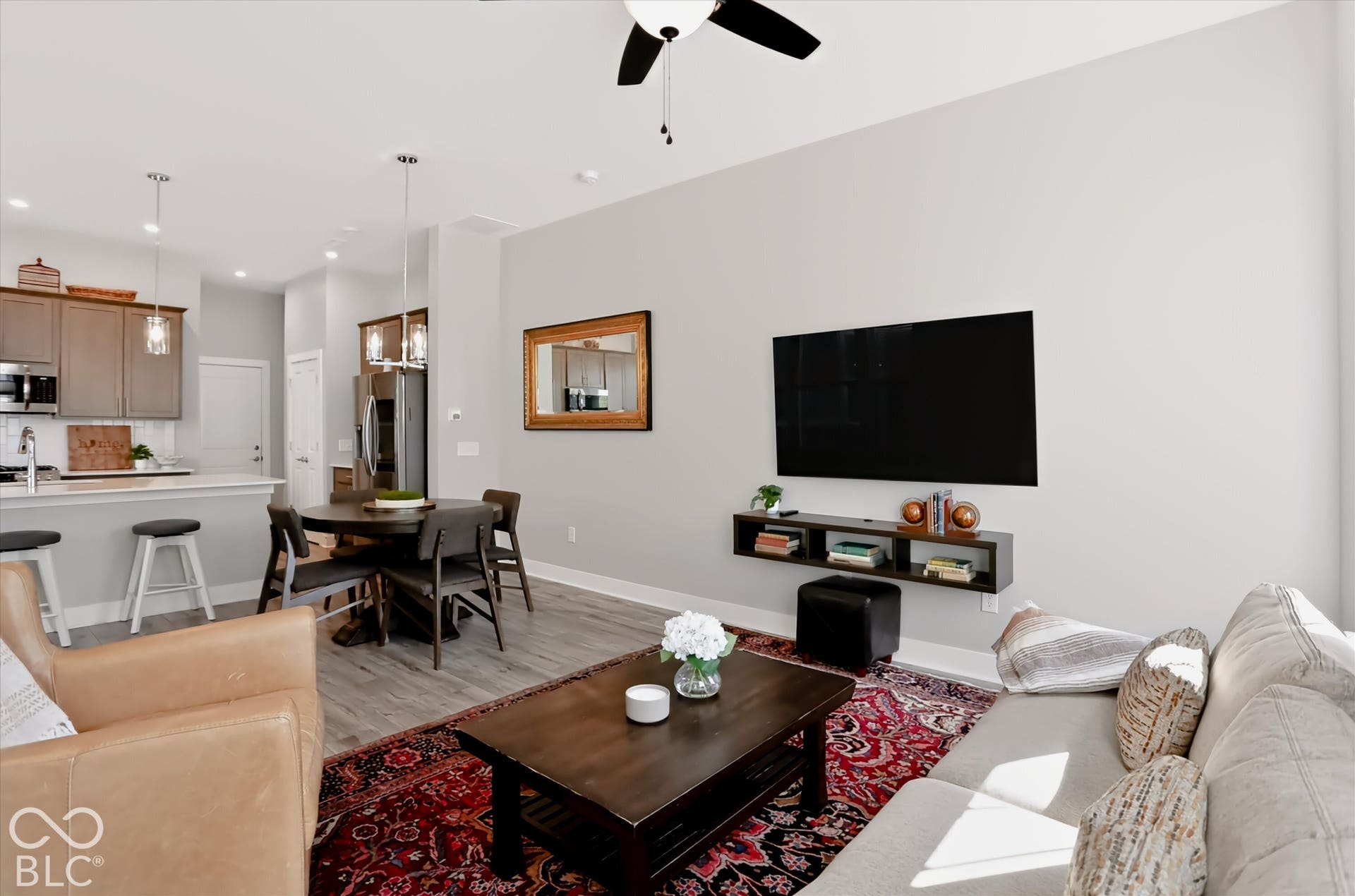 Open-concept living area featuring wood-finish flooring, a contemporary ceiling fan, recessed lighting, and a kitchen island with pendant lighting