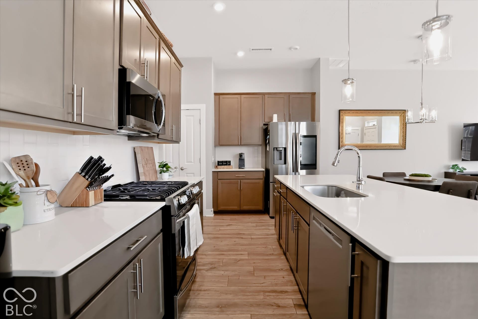 Gourmet kitchen featuring stainless steel appliances, wood-finish flooring, white countertops, and a large island with an undermount sink