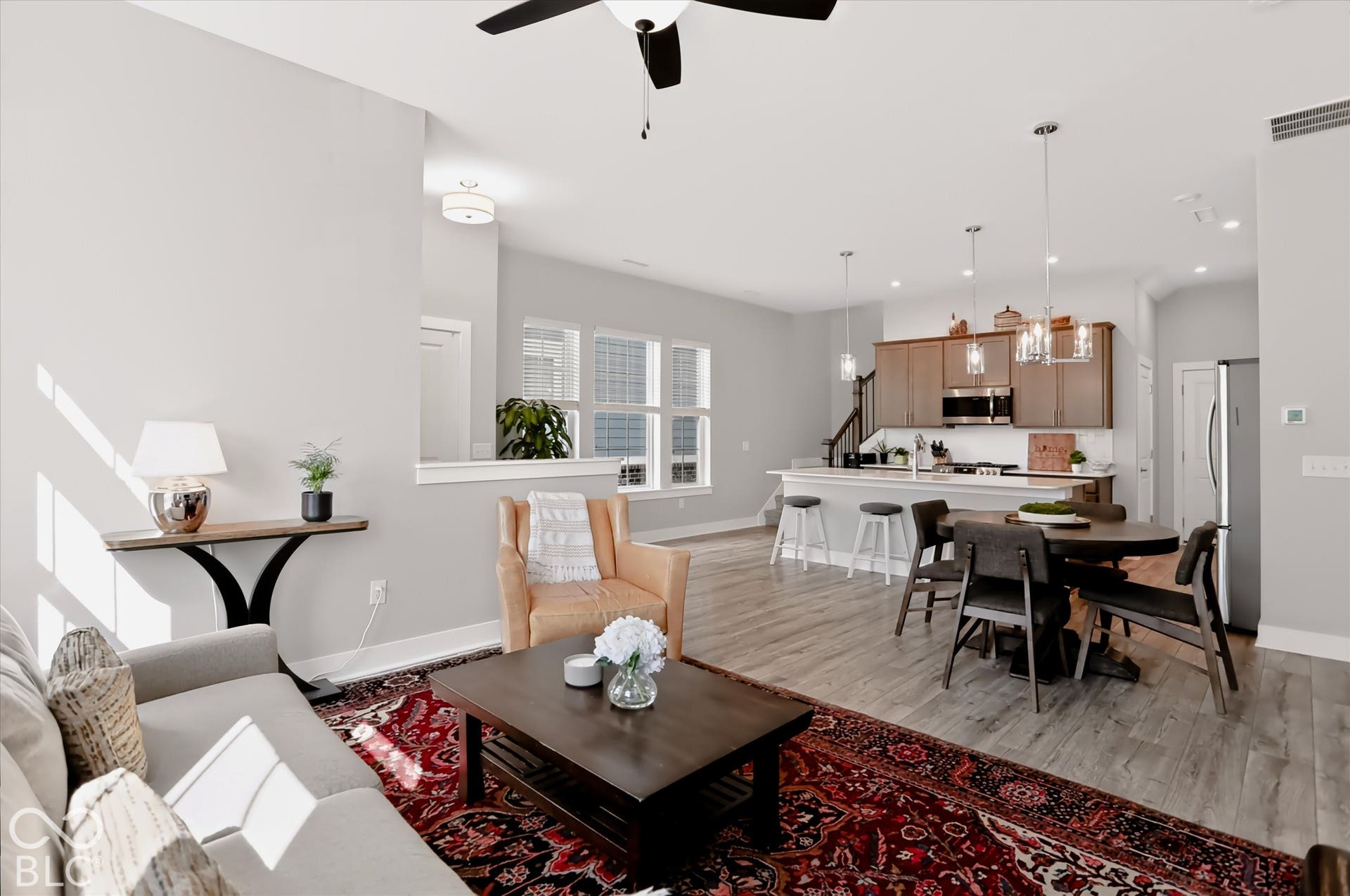 Open-concept living space featuring wood-finish flooring, a kitchen with stainless steel appliances, and an island with bar seating