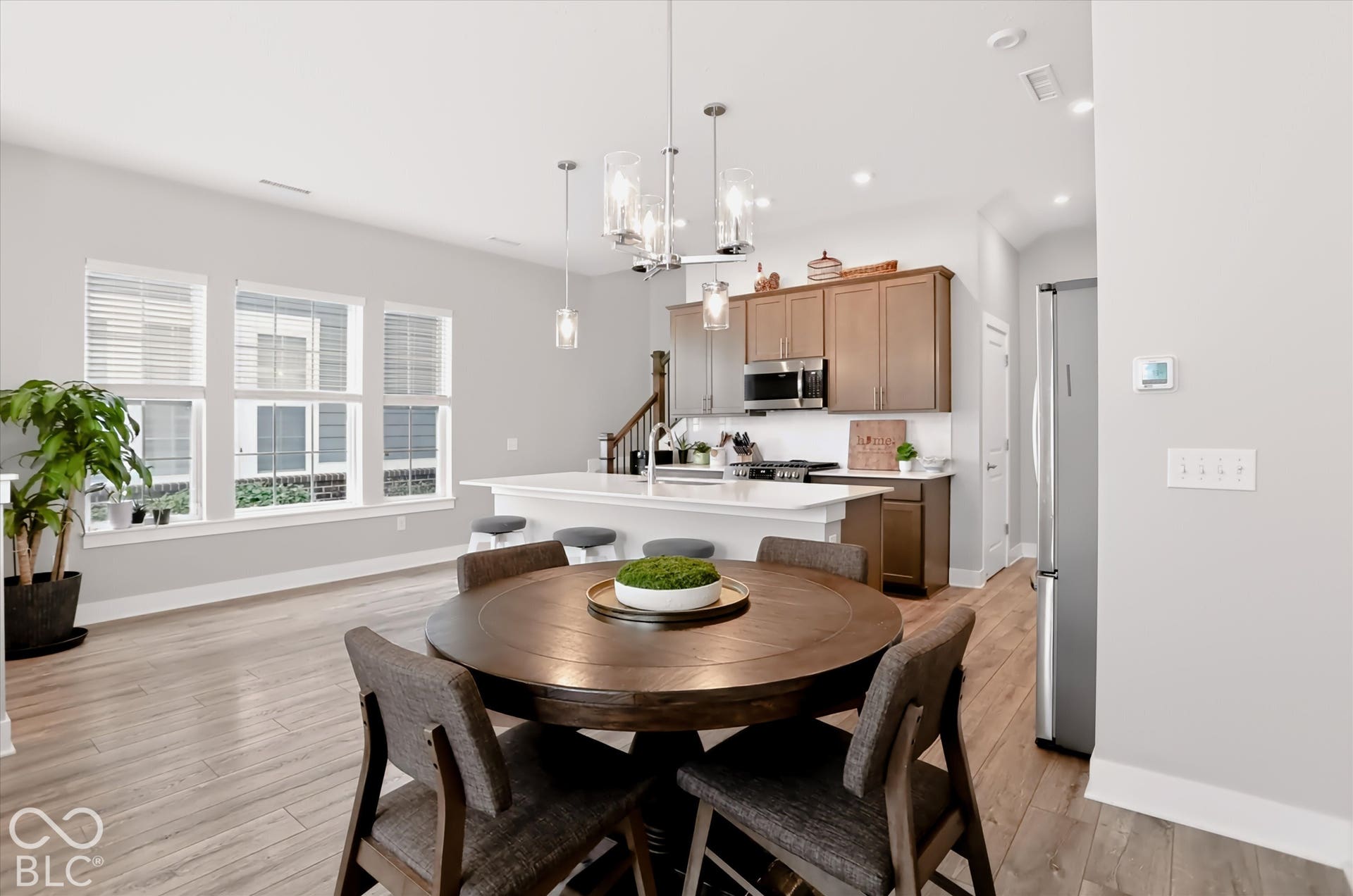 Open-concept kitchen with wood-finish flooring, stainless steel appliances, and an island featuring a white countertop