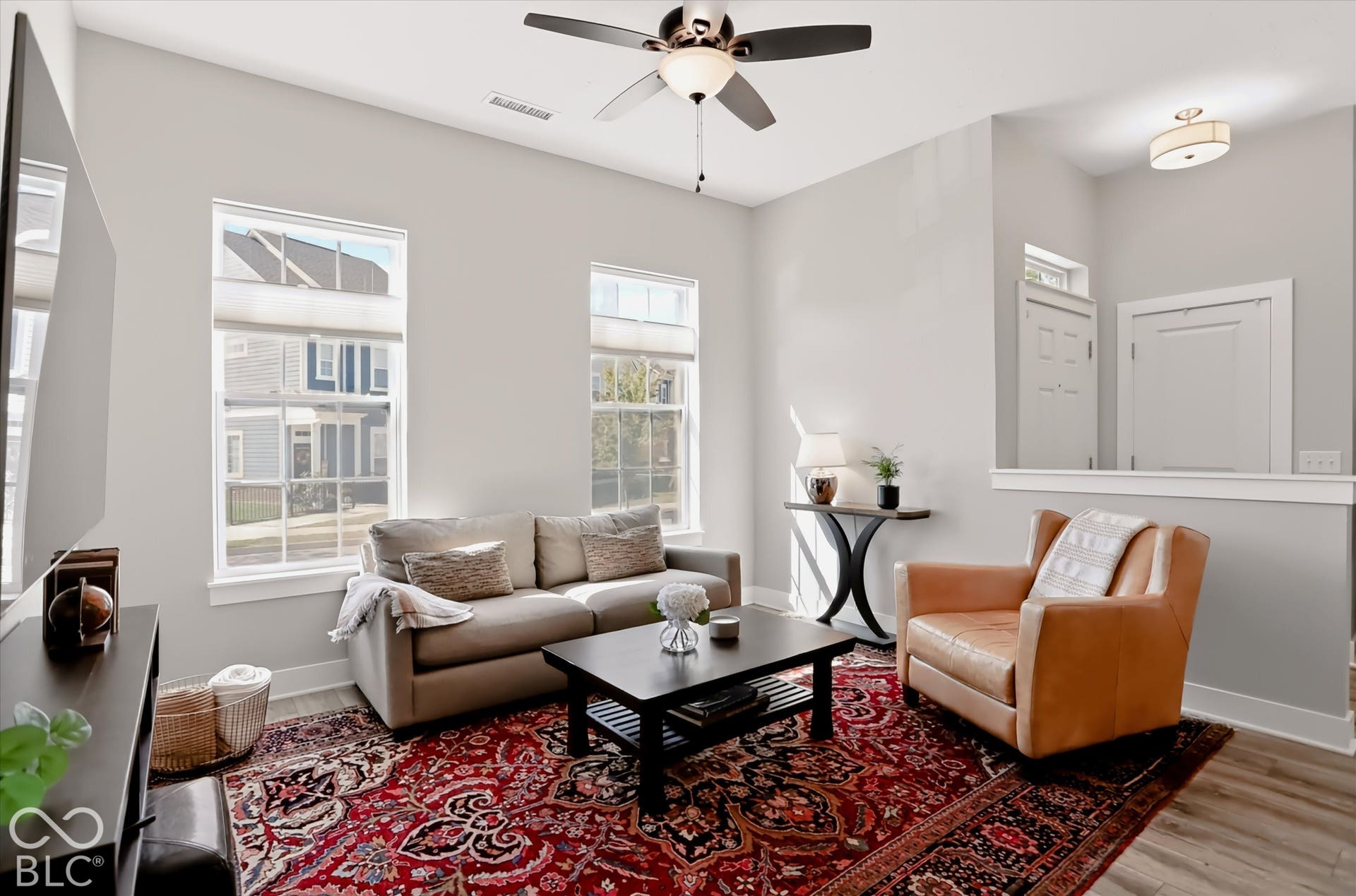 Vaulted ceiling with a ceiling fan light fixture, recessed lighting, wood-finish flooring, two large windows, and a built-in wall partition