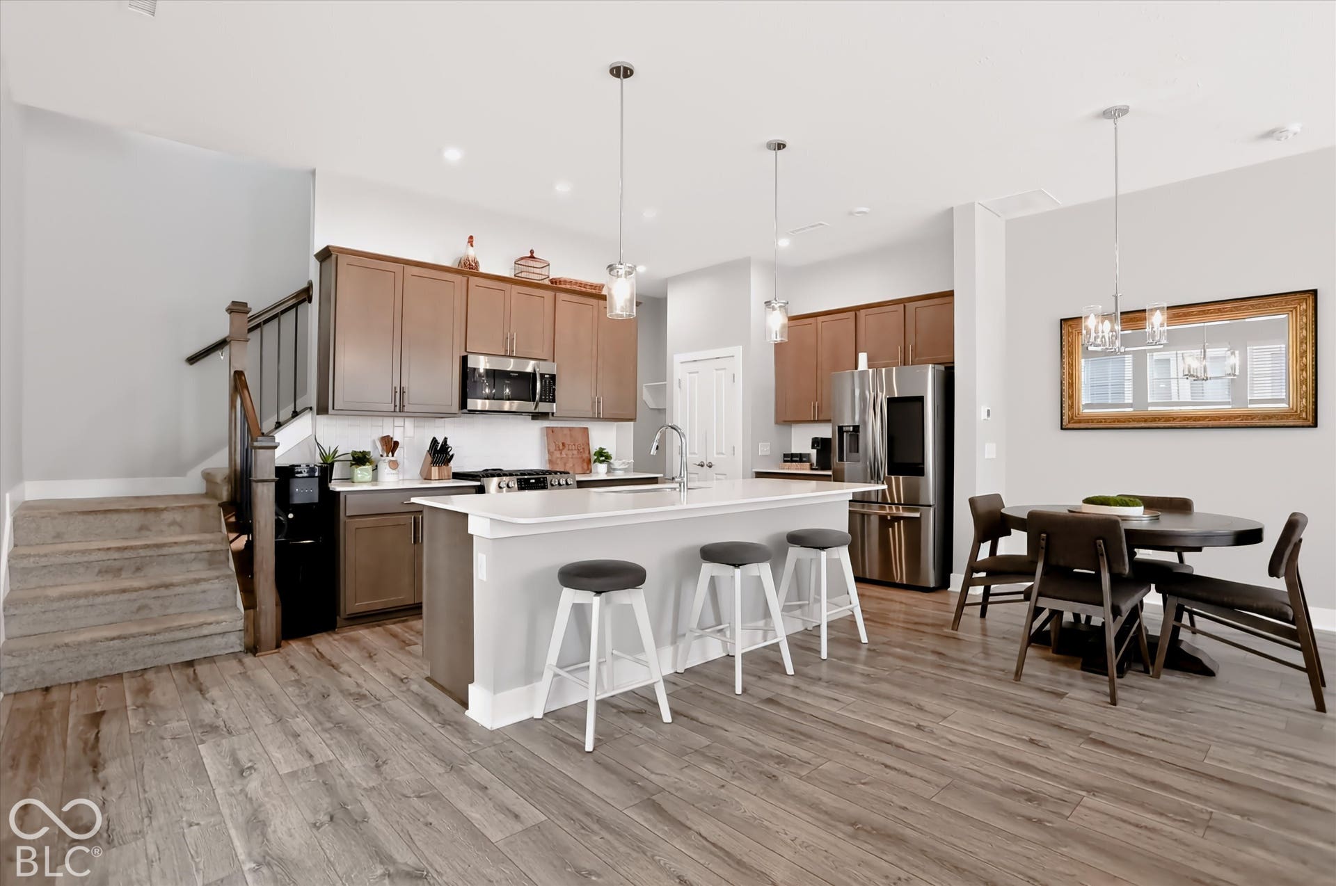 Kitchen featuring wood-finish flooring, stainless steel appliances, white countertops, and a central island with pendant lighting