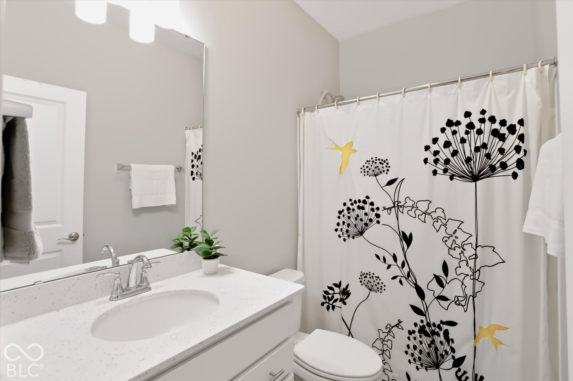 Vanity with integrated sink, polished chrome faucet, and expansive mirror