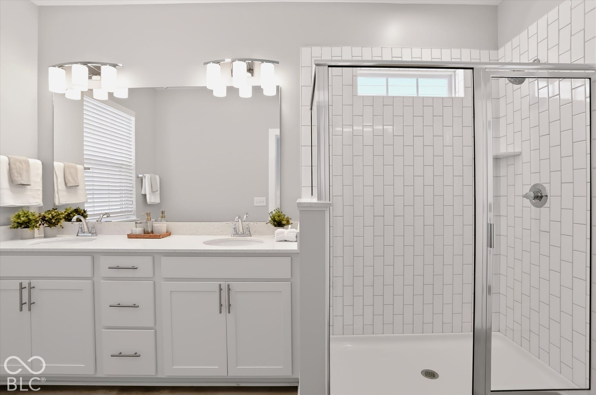 Dual vanity with white cabinetry, polished chrome hardware, and a framed mirror