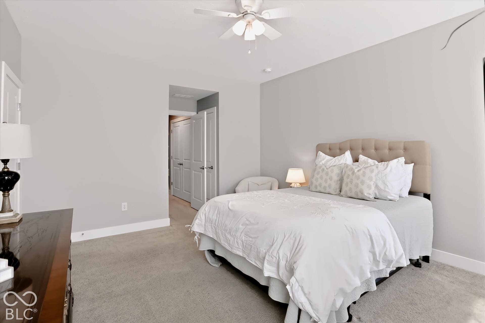 Light gray carpeting, light gray wall paint, and a built-in ceiling fan with light fixture