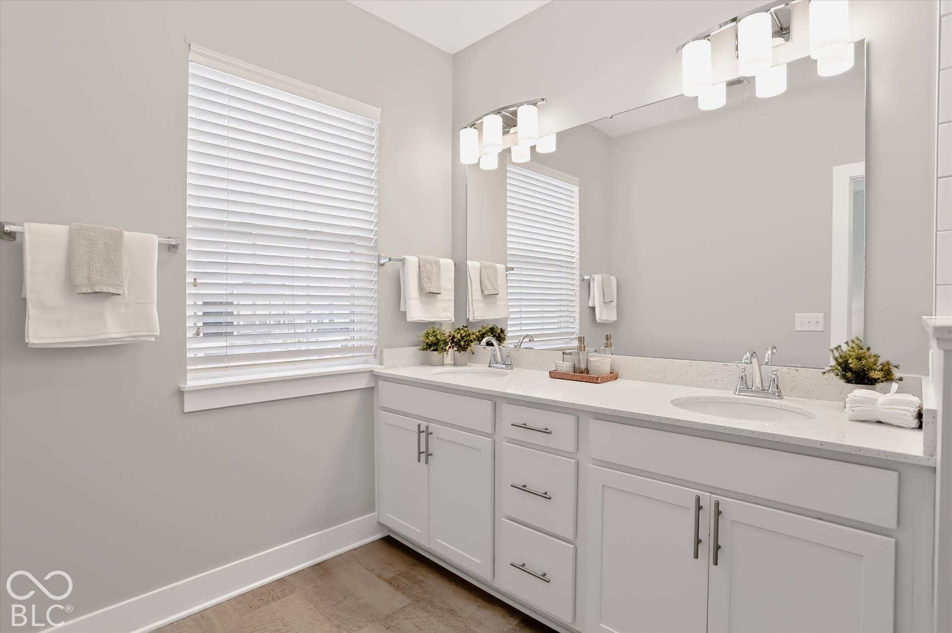 Dual vanity with white cabinetry, light-colored countertops, and chrome fixtures