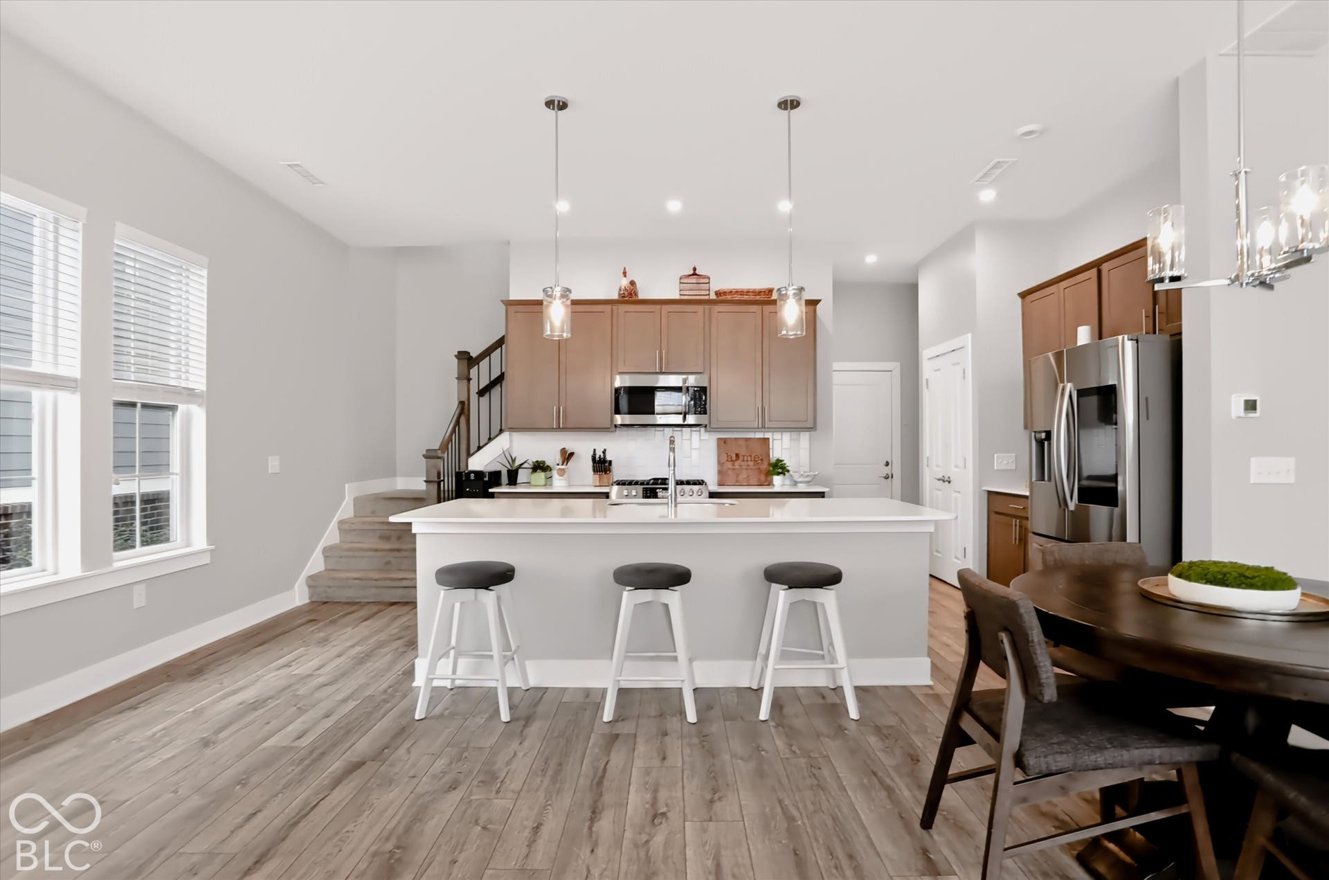 Wood-finish flooring, island with white countertop, stainless steel appliances, pendant lighting, and recessed lighting