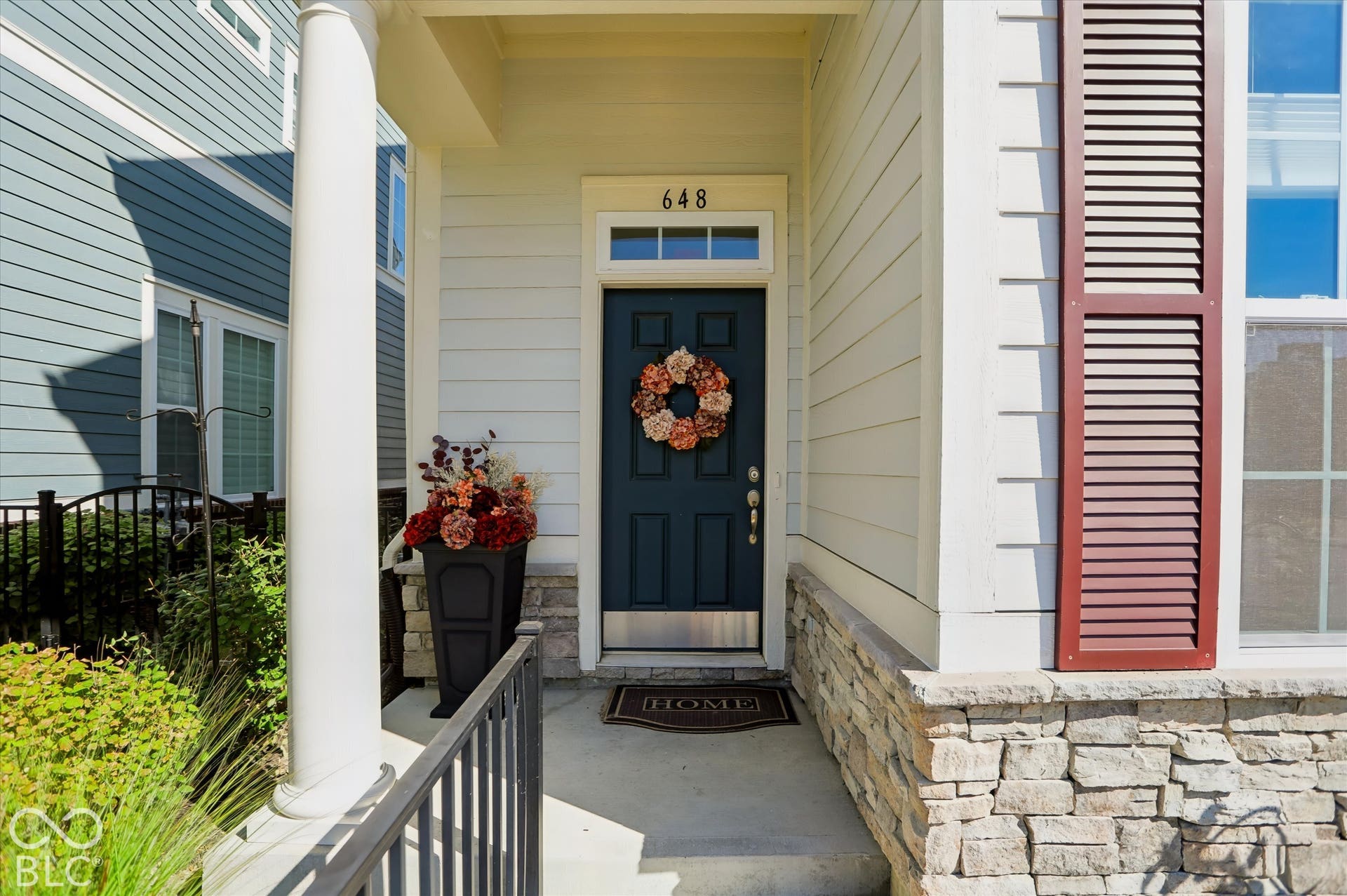 Inviting front entry featuring a dark-paneled door, transom window, and stone veneer foundation