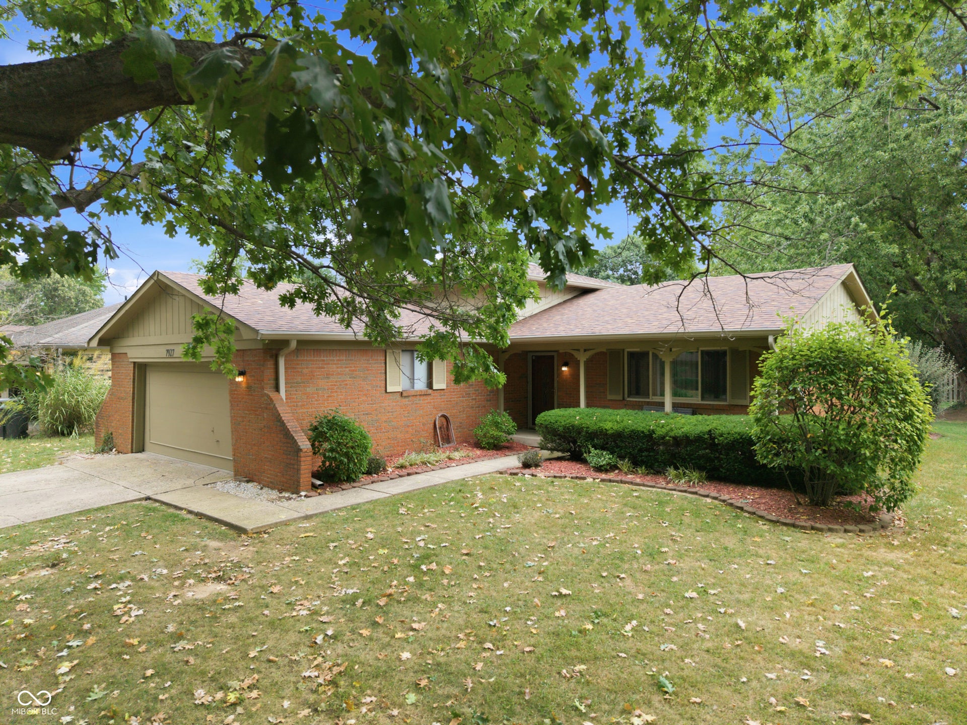 7927 Hoop Road, Indianapolis, IN 46217 Brick exterior with a covered porch, attached garage, and mature landscaping