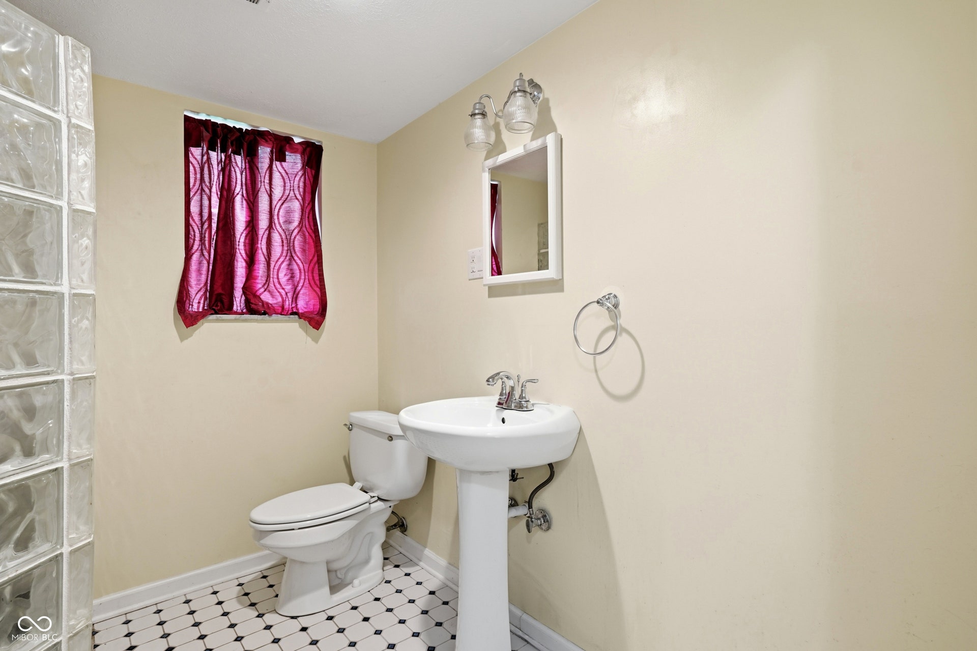 7927 Hoop Road, Indianapolis, IN 46217 Lower level, pedestal sink with chrome faucet, toilet, tile floors, and glass block wall