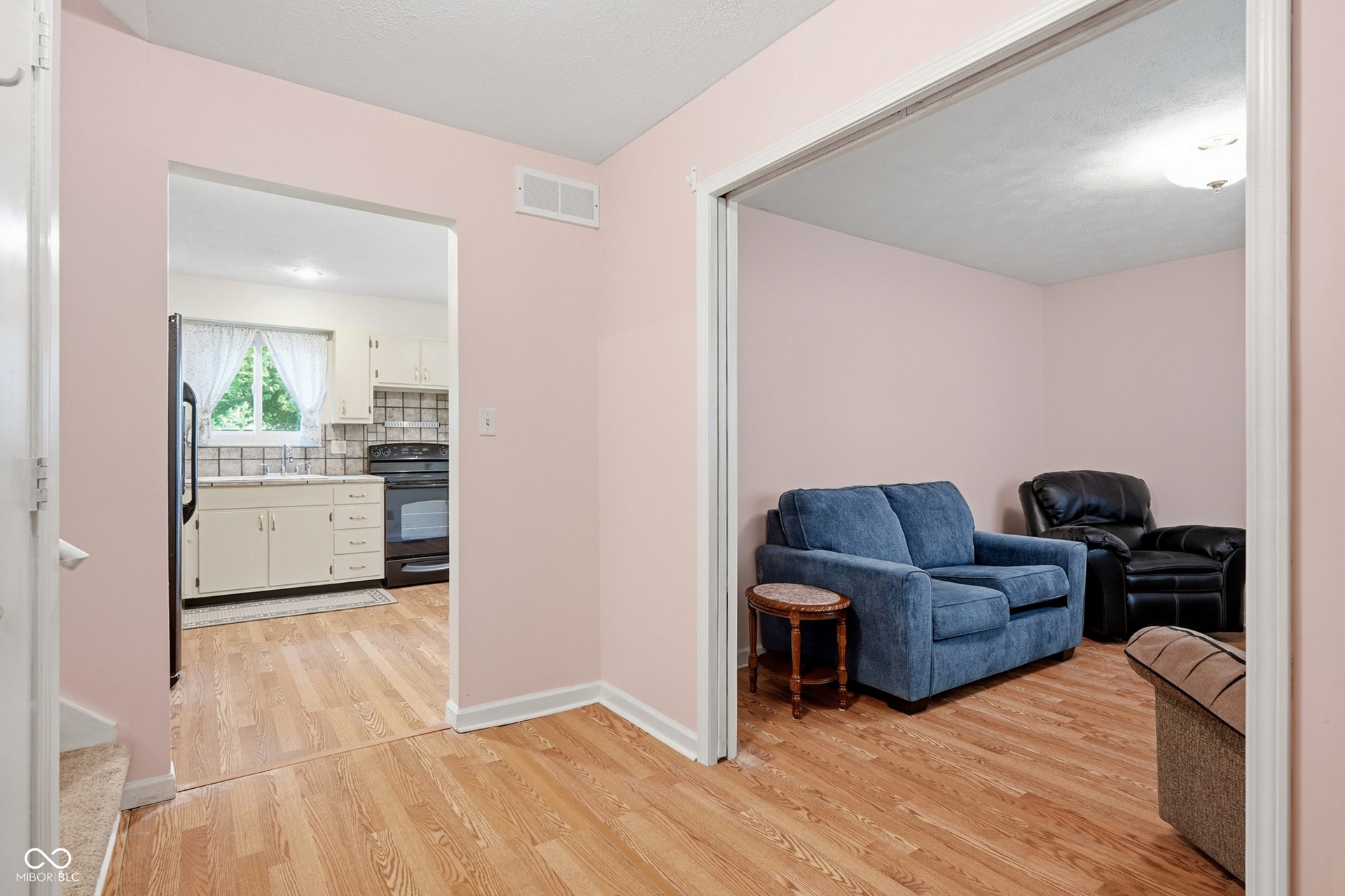 7927 Hoop Road, Indianapolis, IN 46217 Wood-finish laminate flooring throughout main level, with a kitchen visible through an archway, and pocket doors leading into living room