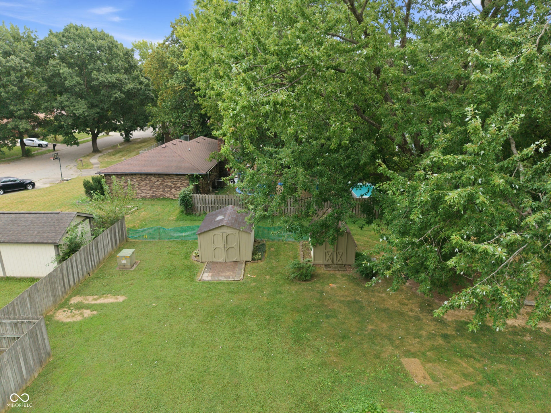 7927 Hoop Road, Indianapolis, IN 46217 Expansive grassy yard featuring a wooden privacy fence, two storage sheds, and mature trees