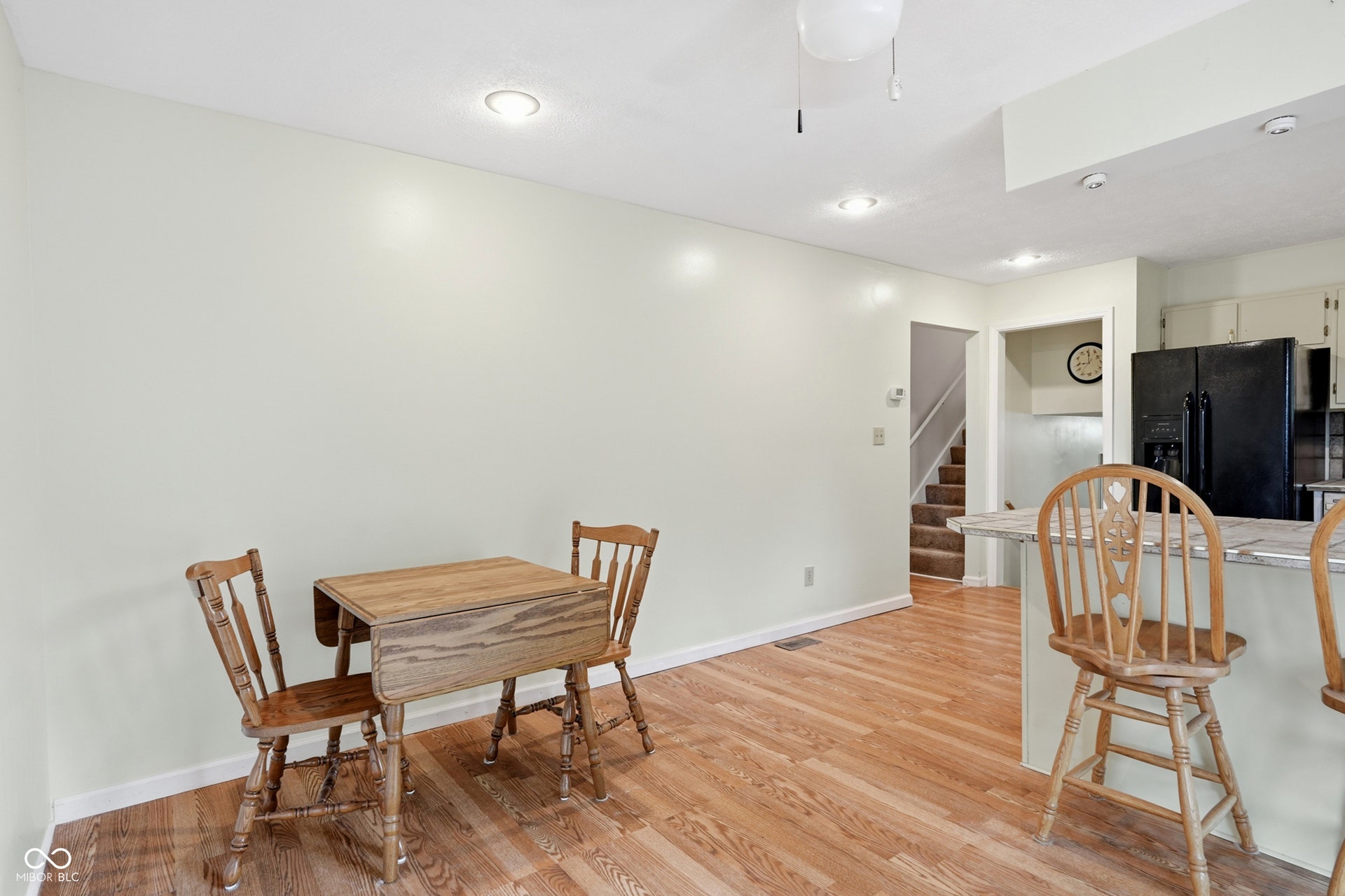 7927 Hoop Road, Indianapolis, IN 46217 Recessed lighting, wood-finish laminate flooring, kitchen bar with stone-look tile countertop, white painted walls, staircase with carpeted treads