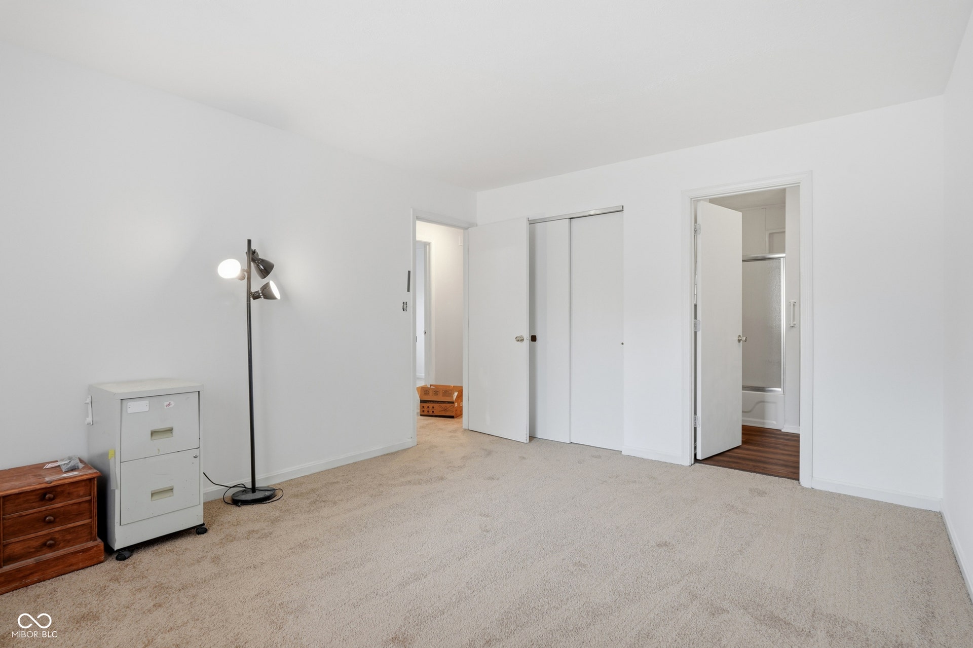 7927 Hoop Road, Indianapolis, IN 46217 Upper level primary bedroom, light-toned wall-to-wall carpeting, white painted walls, and white bi-fold closet doors