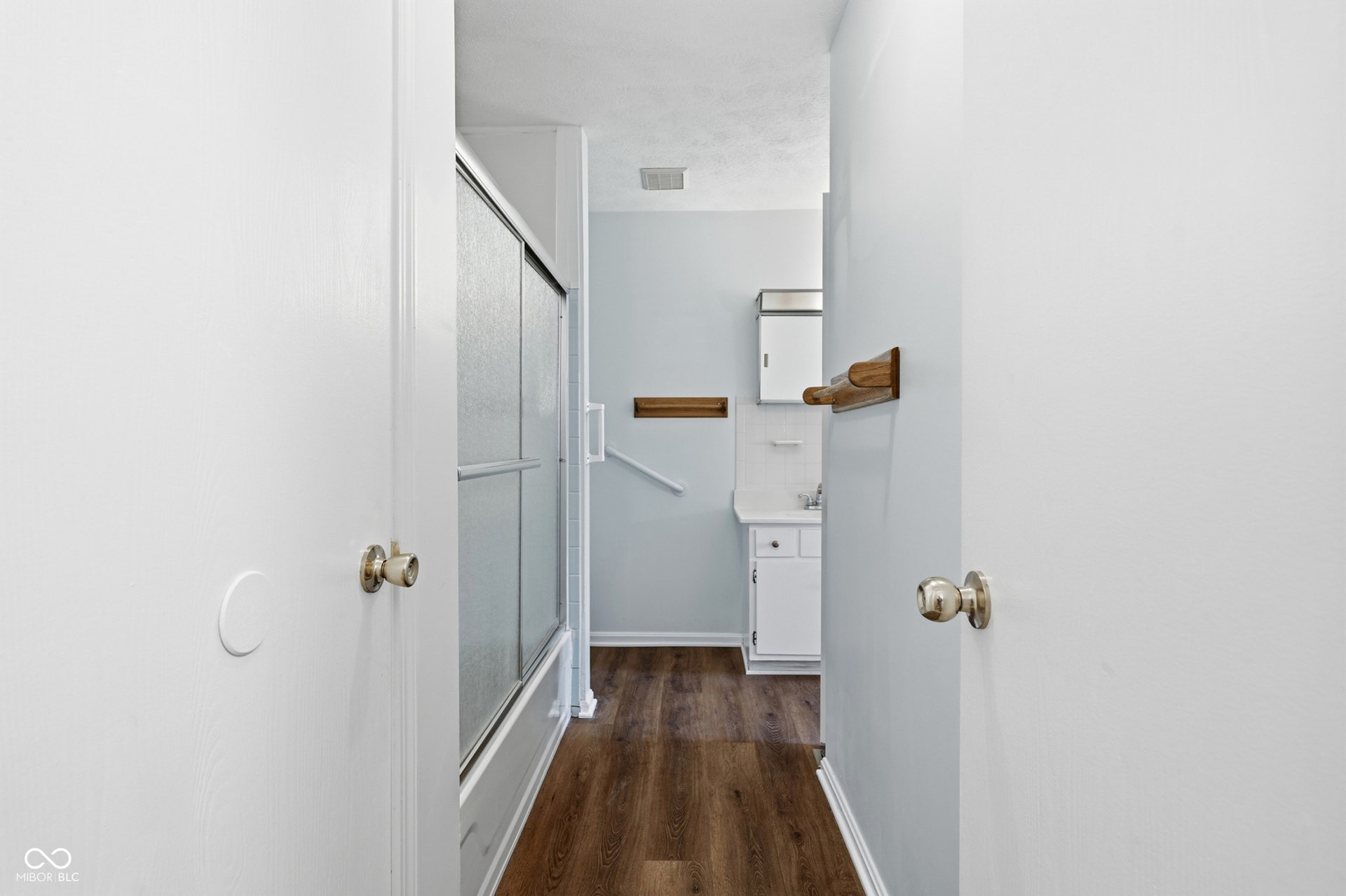 7927 Hoop Road, Indianapolis, IN 46217 Upper level full bath, wood-finish laminate flooring, white vanity, mirrored medicine cabinet, and a shower with sliding glass doors