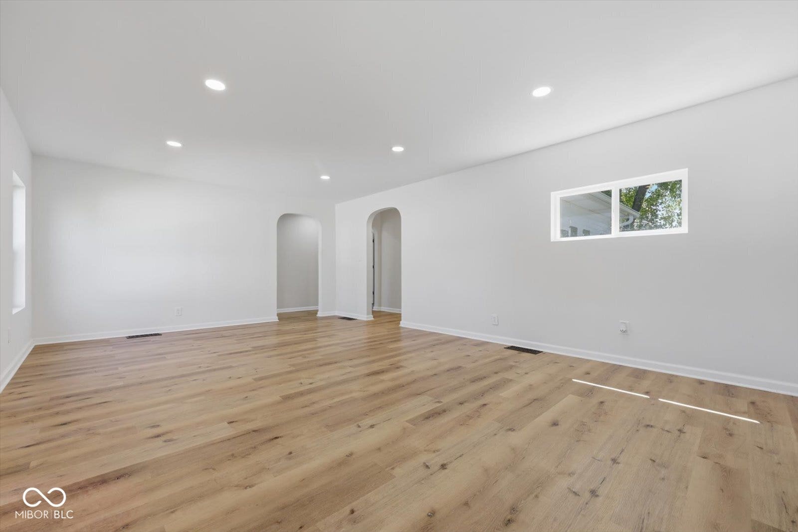 Spacious interior with wood-finish flooring, recessed lighting, and arched doorways