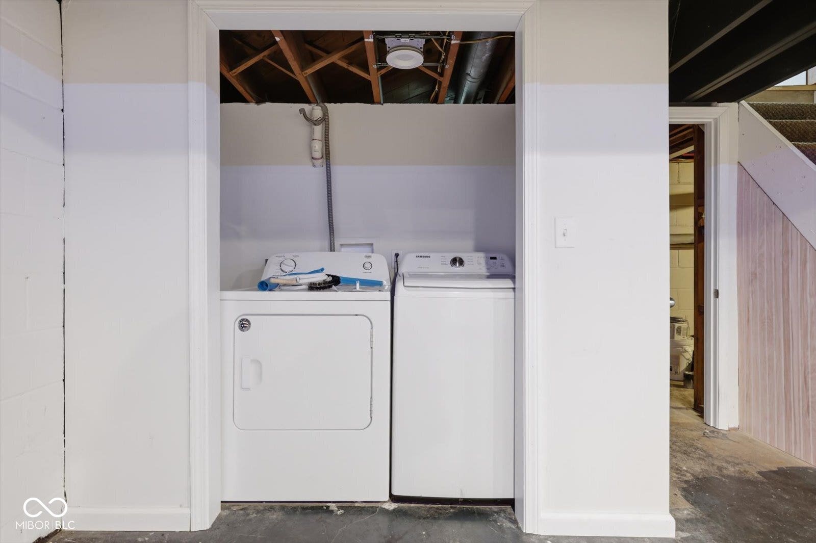 Laundry area with exposed ceiling joists and included appliances