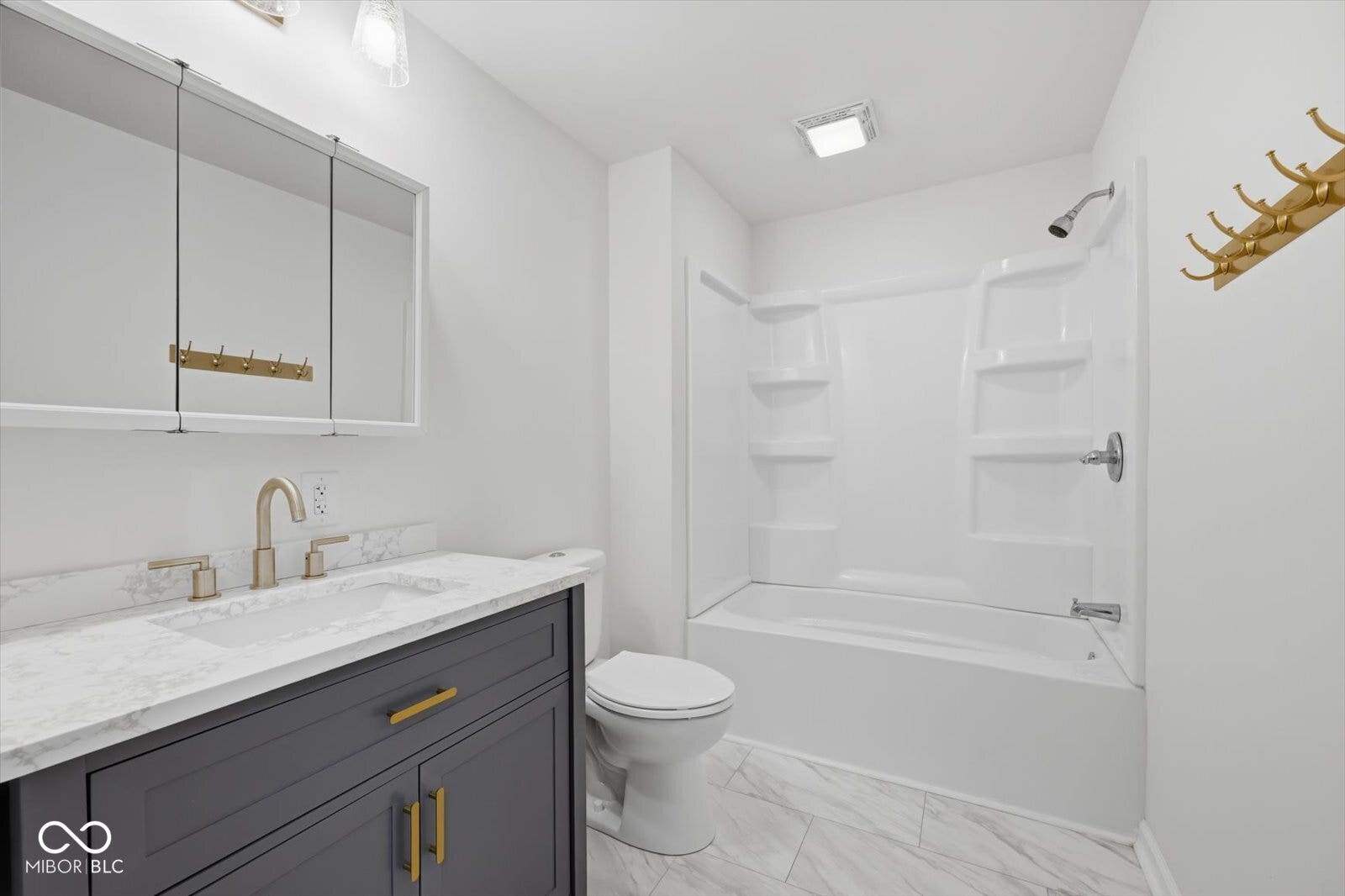 Modern bathroom with a dark gray vanity, white countertop, and gold-finish hardware