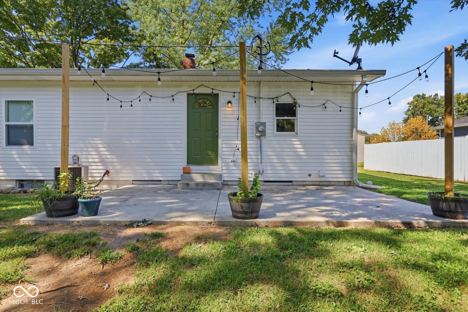Concrete patio with a green exterior door and white siding