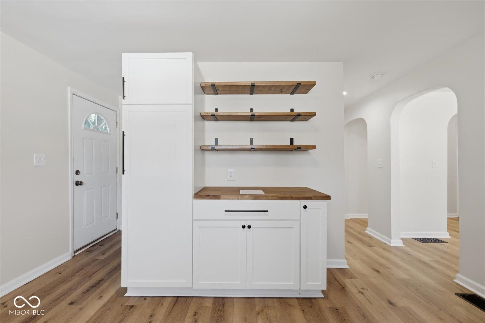 Wood-finish flooring throughout, complemented by white cabinetry with black hardware