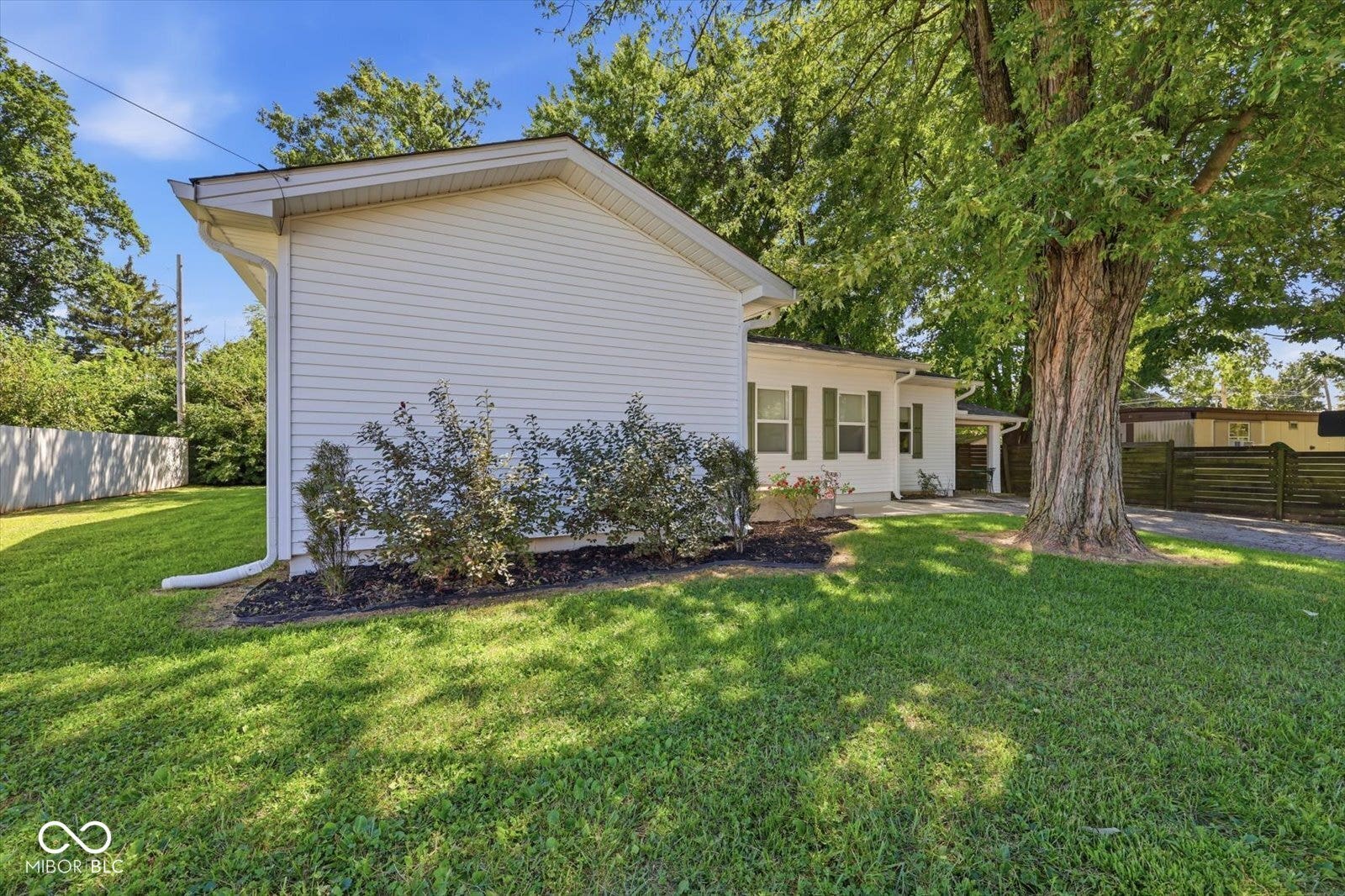 White siding exterior with a pitched roof, green shutters, and established landscaping