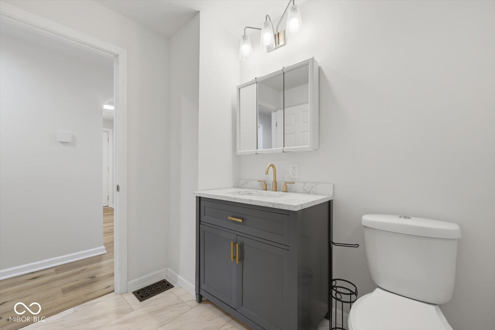 Modern vanity with a gray finish, white countertop, and gold-toned faucet