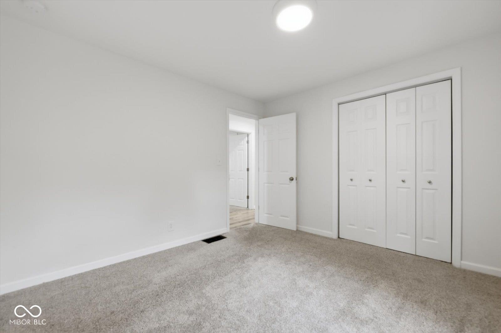 Neutral paint palette with carpeted flooring, a flush-mount ceiling light, and bi-fold closet doors