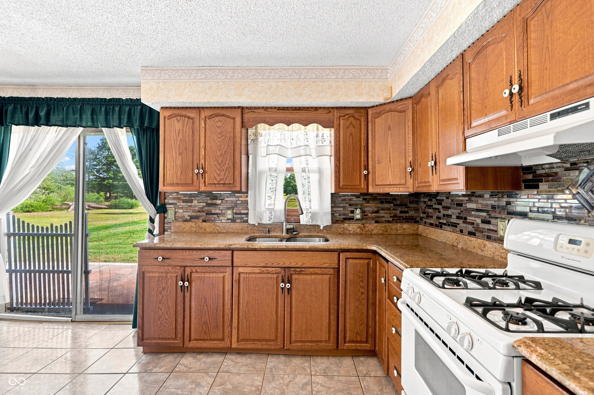 14 x 11 Kitchen with tile floors, updated cabinets, granite counter tops, glass tile splashback plus space for table and chairs with patio access.