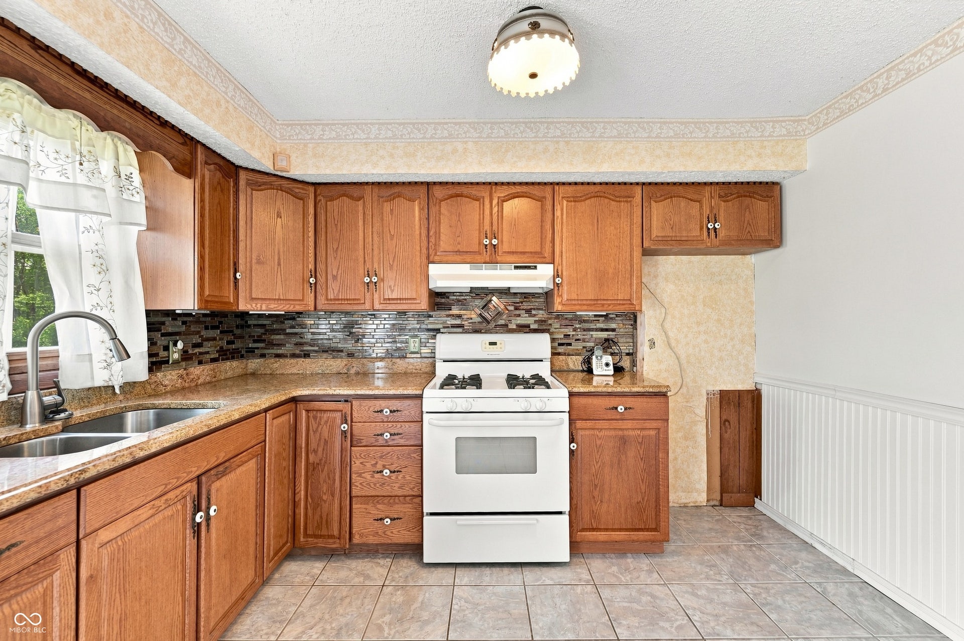 14 x 11 Kitchen with tile floors, updated cabinets, granite counter tops, glass tile splashback plus space for table and chairs with patio access.